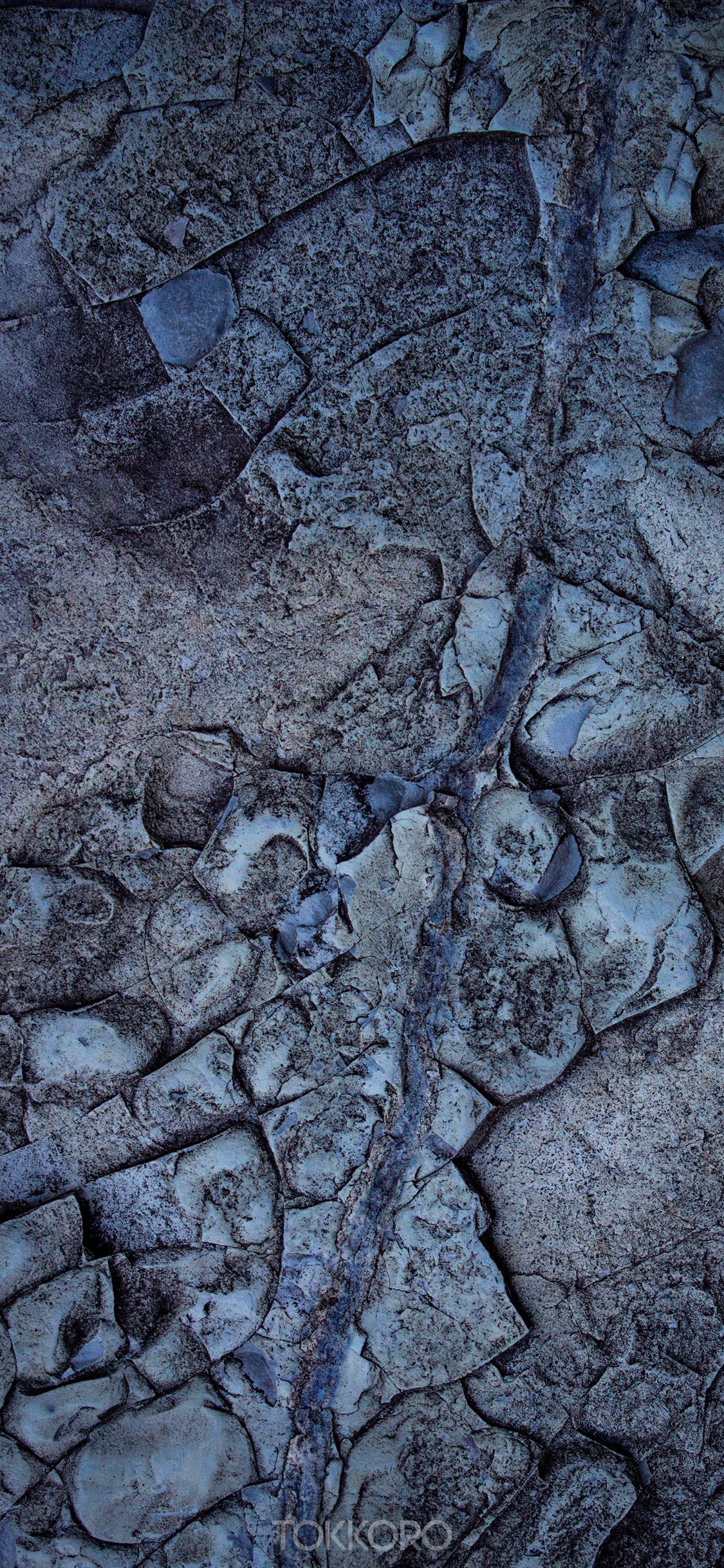 Close-up of a textured rock surface with a blue vein HD Phone Wallpaper