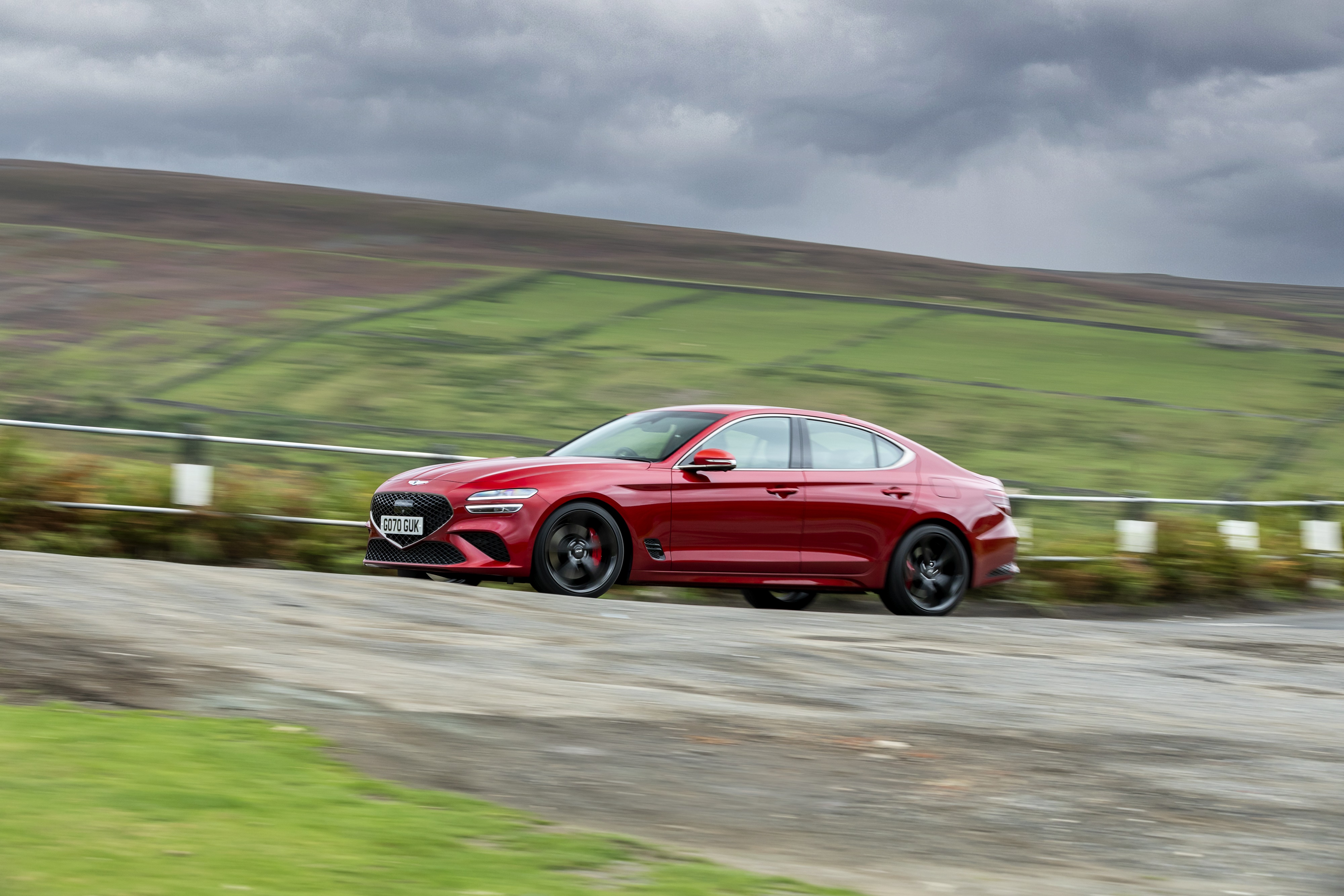 Red Genesis G70 2.0T driving on a rural road HD Wallpaper