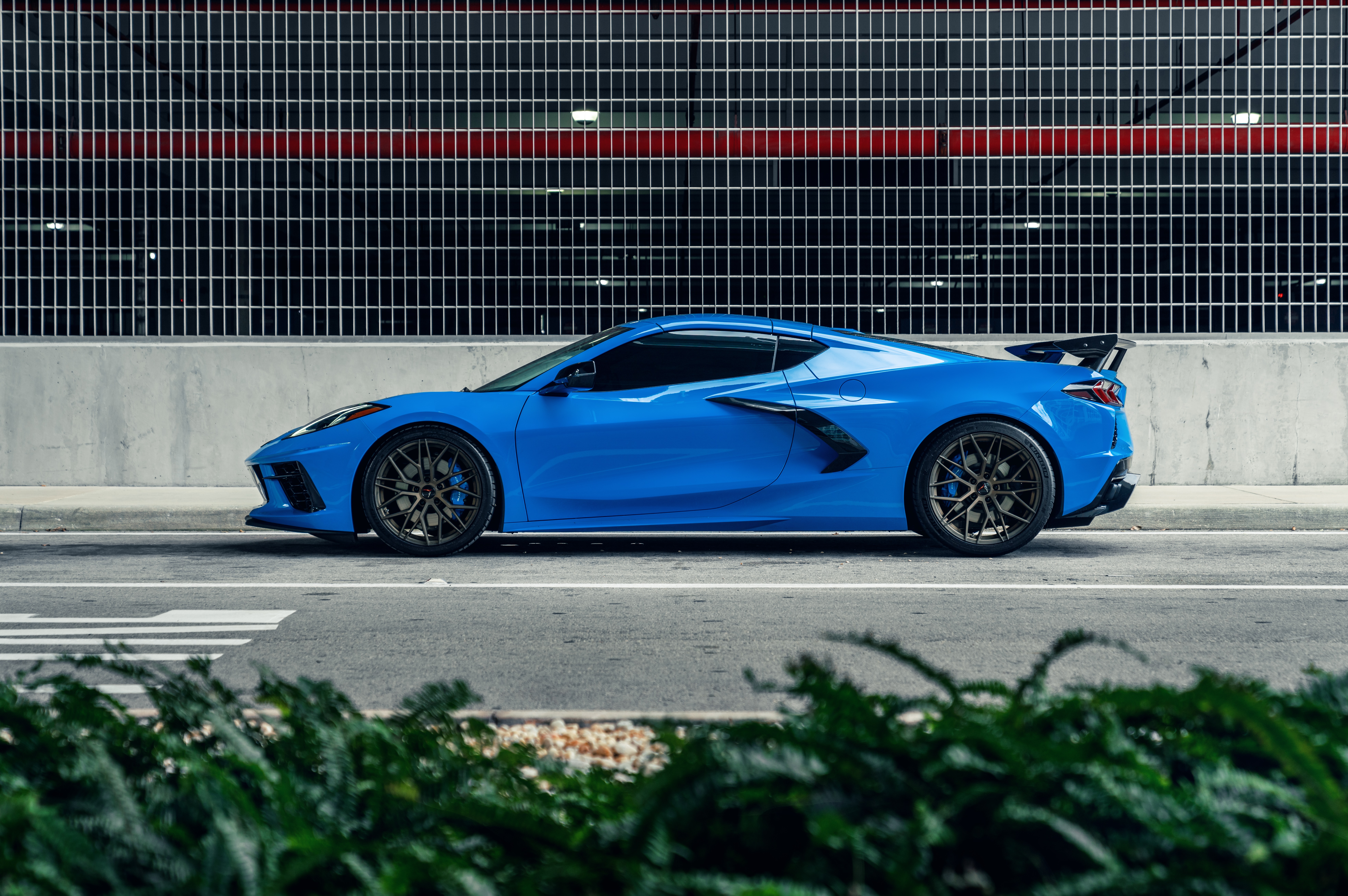 Blue Chevrolet C8 Corvette parked by a building HD Wallpaper