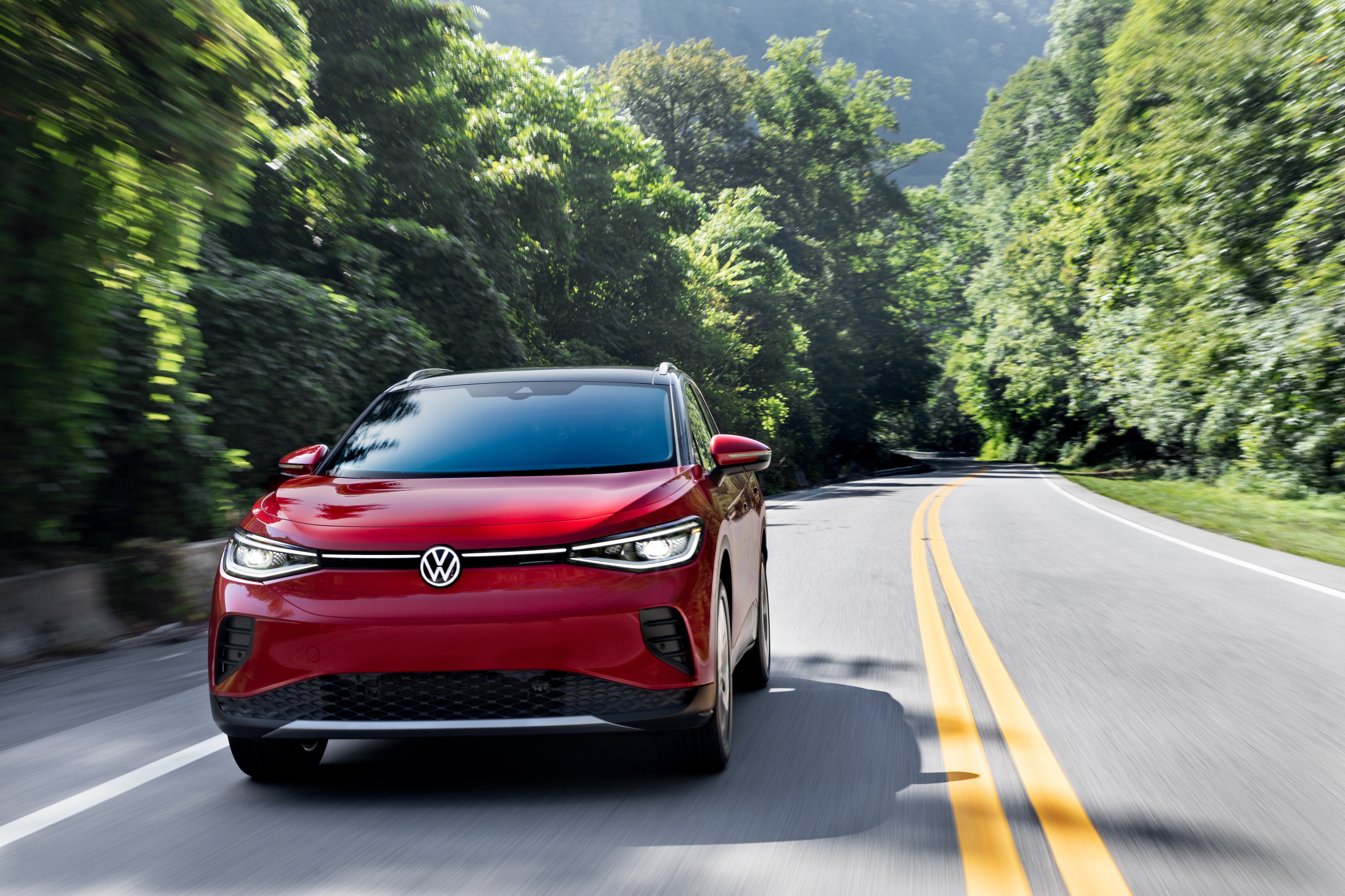 Red Volkswagen ID.4 AWD Pro S driving on a scenic road HD Wallpaper