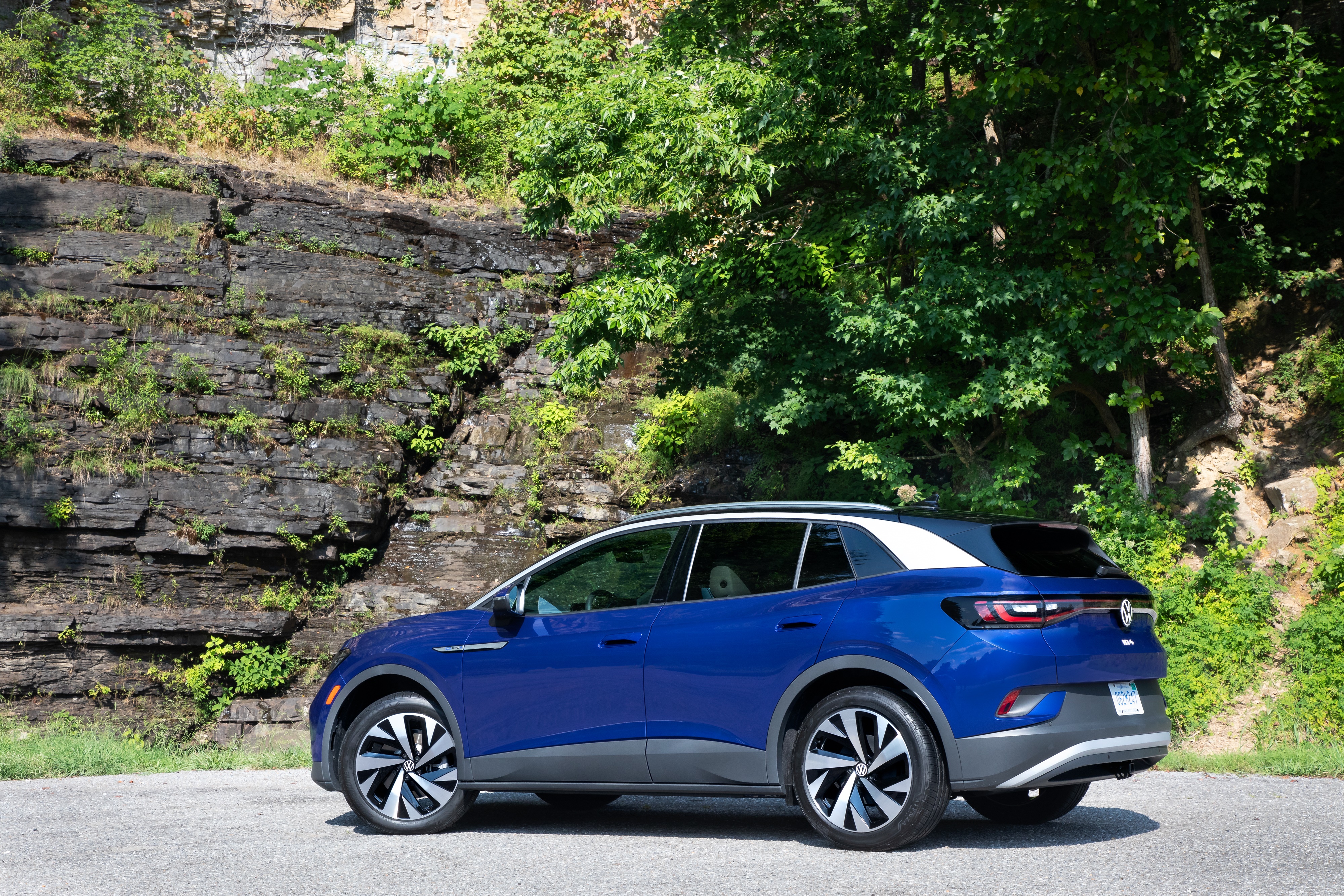 Blue Volkswagen ID.4 AWD Pro S parked by a rocky cliff HD Wallpaper