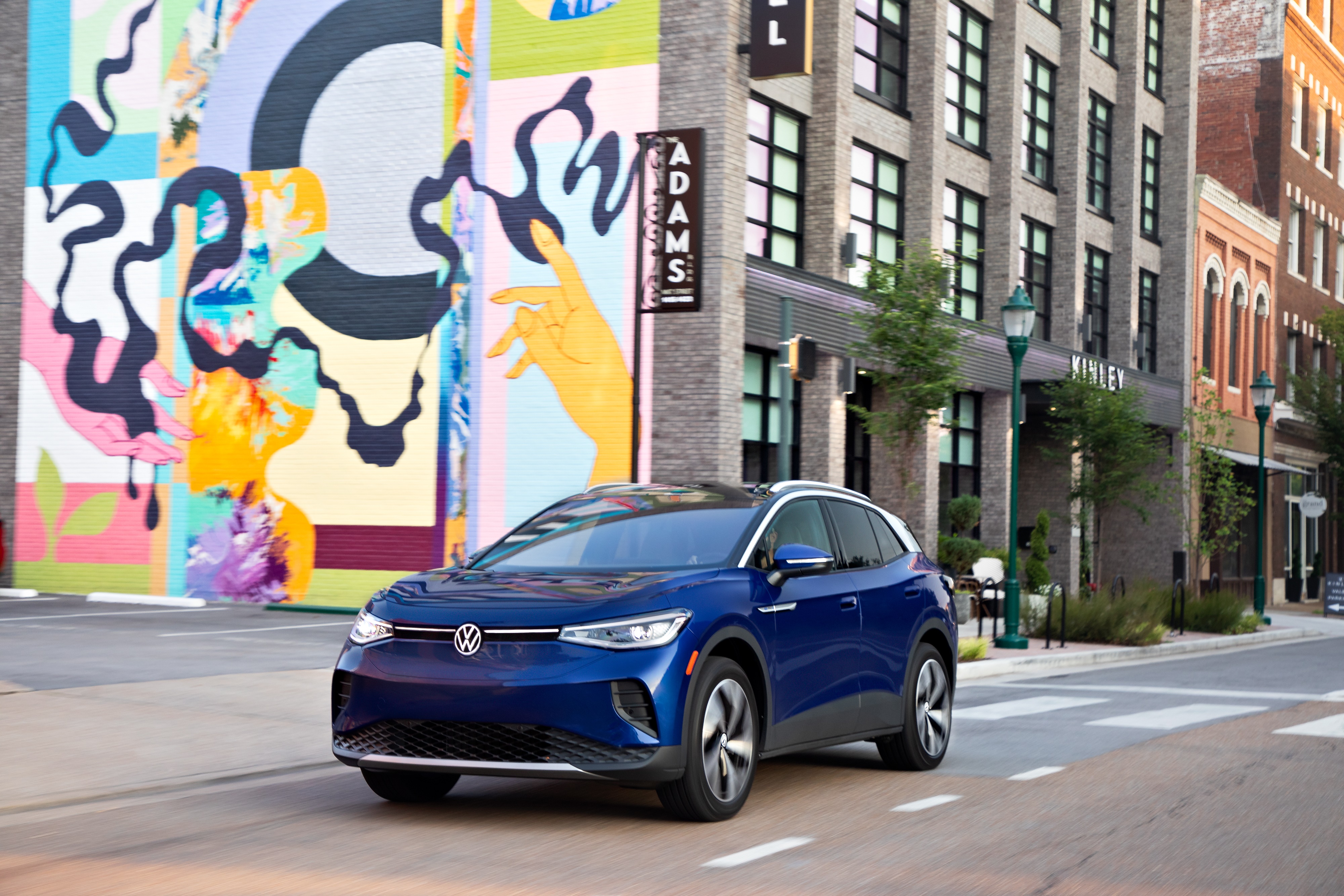 Blue Volkswagen ID.4 electric car driving on city street HD Wallpaper