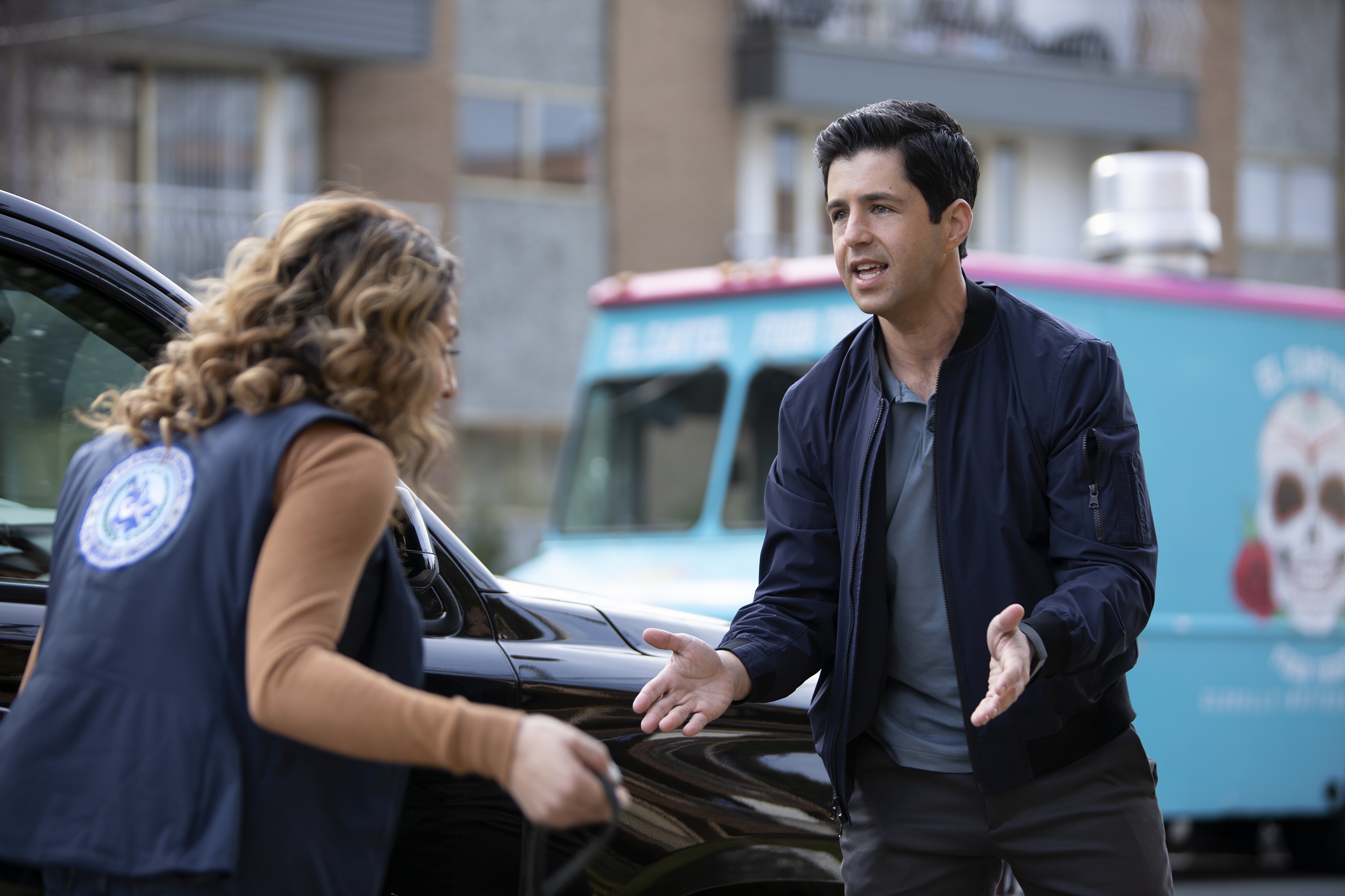 Josh Peck and woman in vest near car and food truck HD Wallpaper