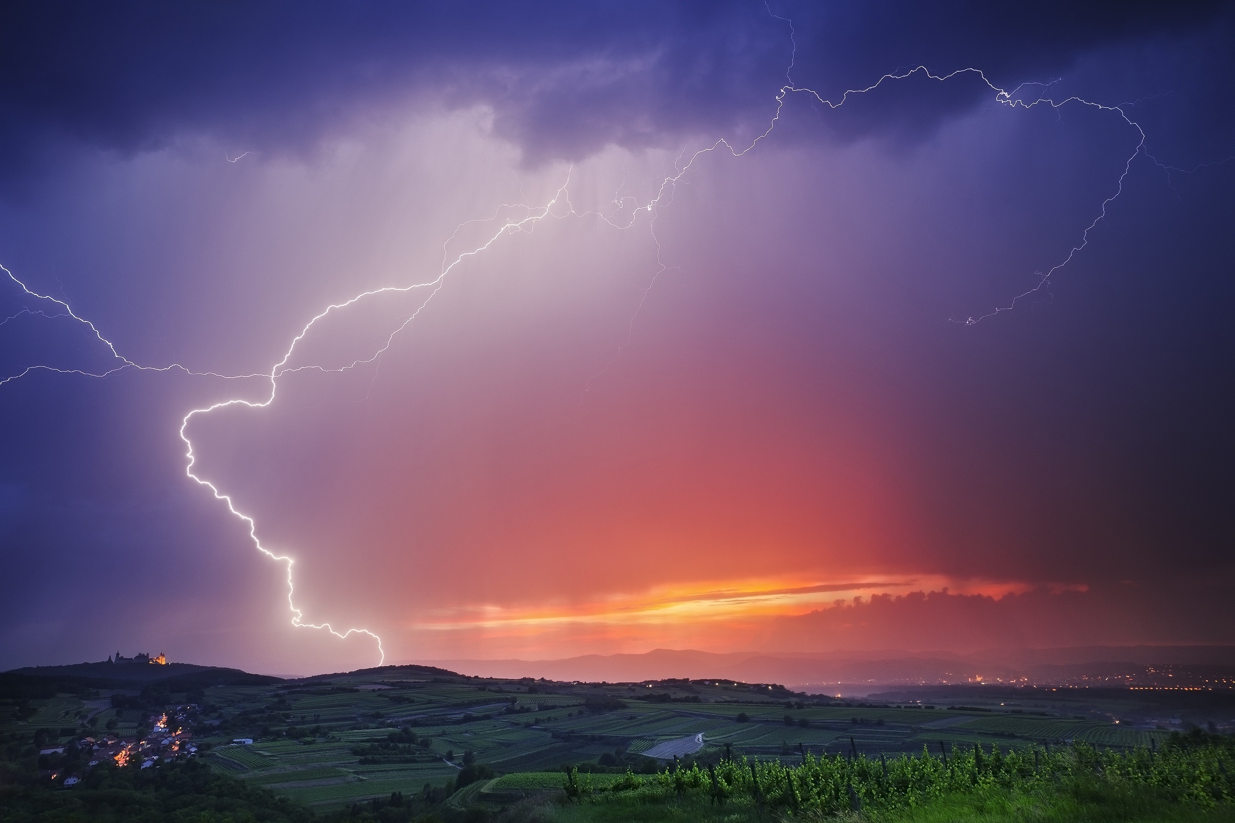 Lightning storm over vineyards and a castle at dusk HD Wallpaper