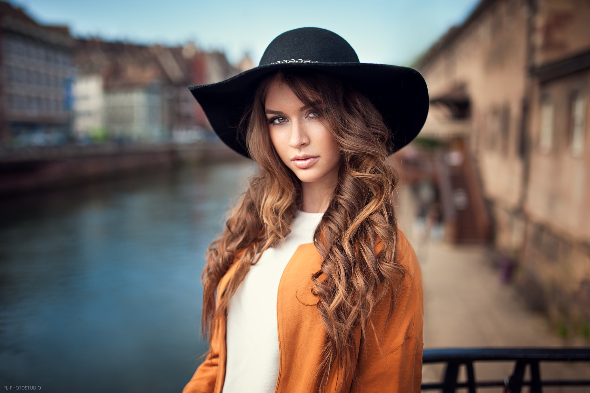 Woman with long curly hair wearing a black hat and orange cardigan HD Wallpaper