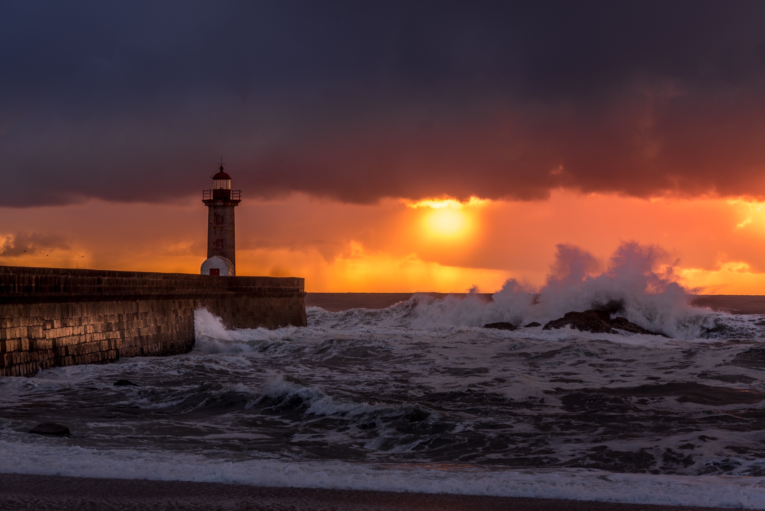 Lighthouse at sunset with crashing waves HD Wallpaper