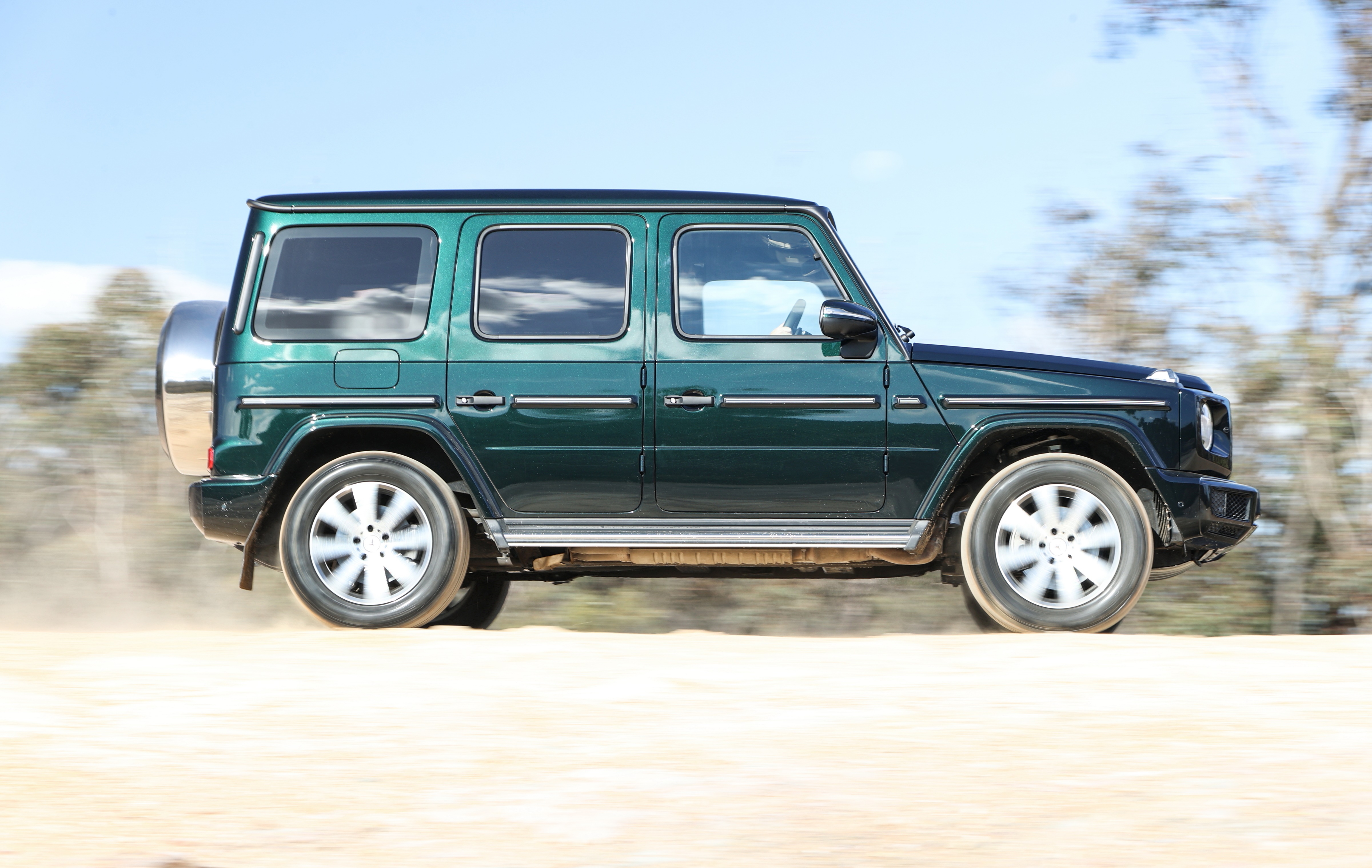Green Mercedes-Benz G-Class driving on dirt road HD Wallpaper