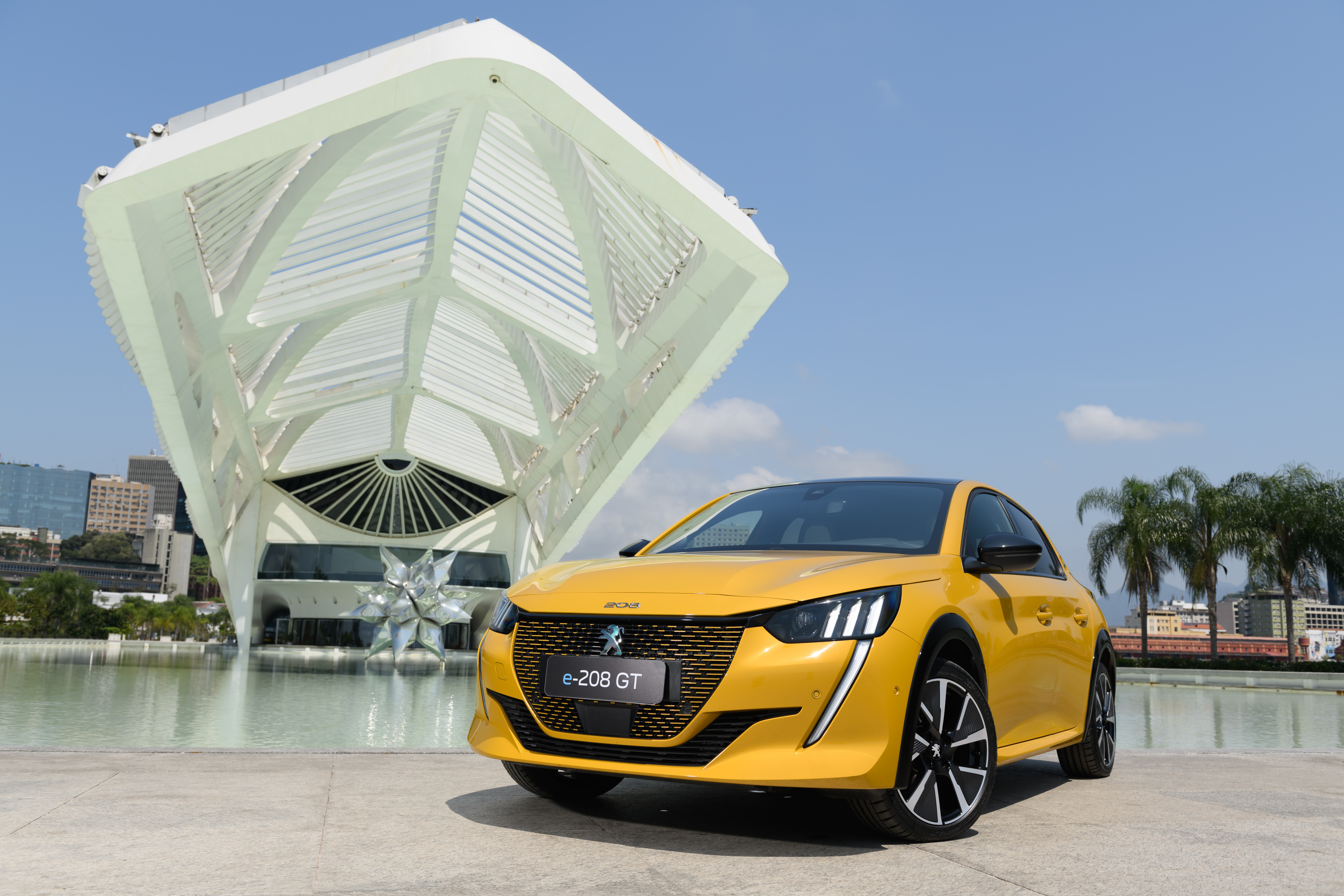 Yellow Peugeot E-208 GT electric car in front of Museum of Tomorrow HD Wallpaper
