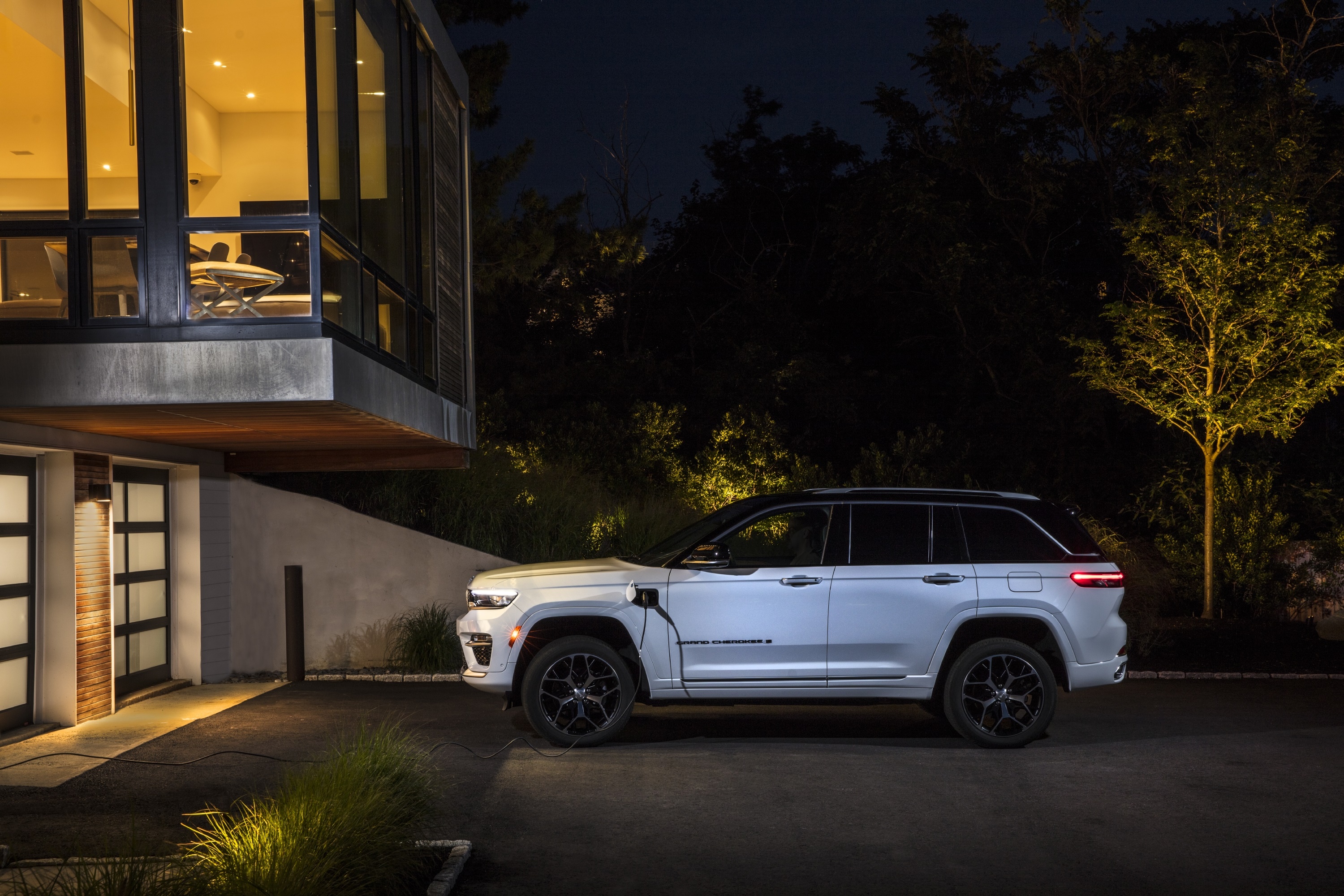 2022 Jeep Grand Cherokee Summit Reserve 4xe charging at modern house HD Wallpaper