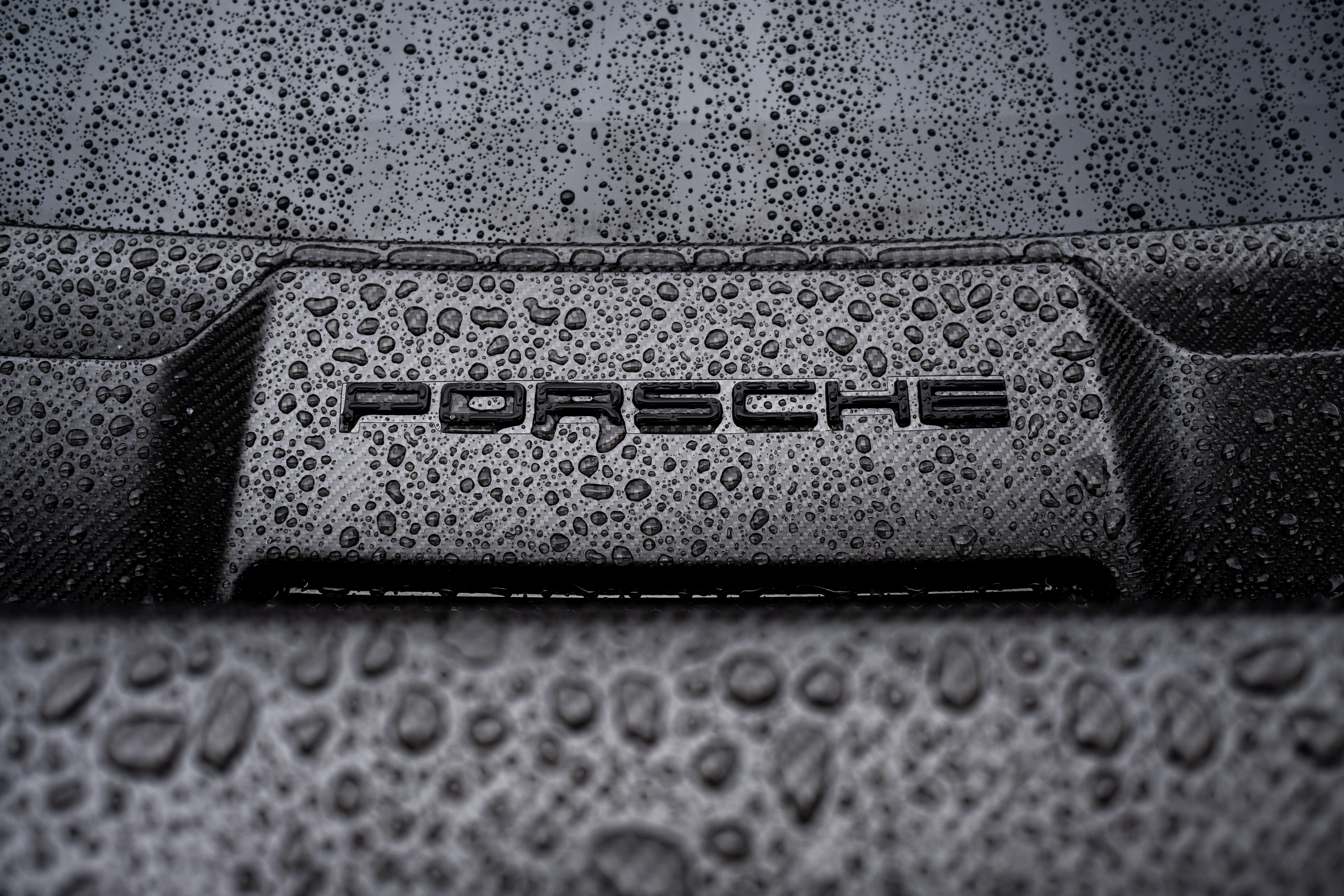 Porsche logo on a car in the rain HD Wallpaper