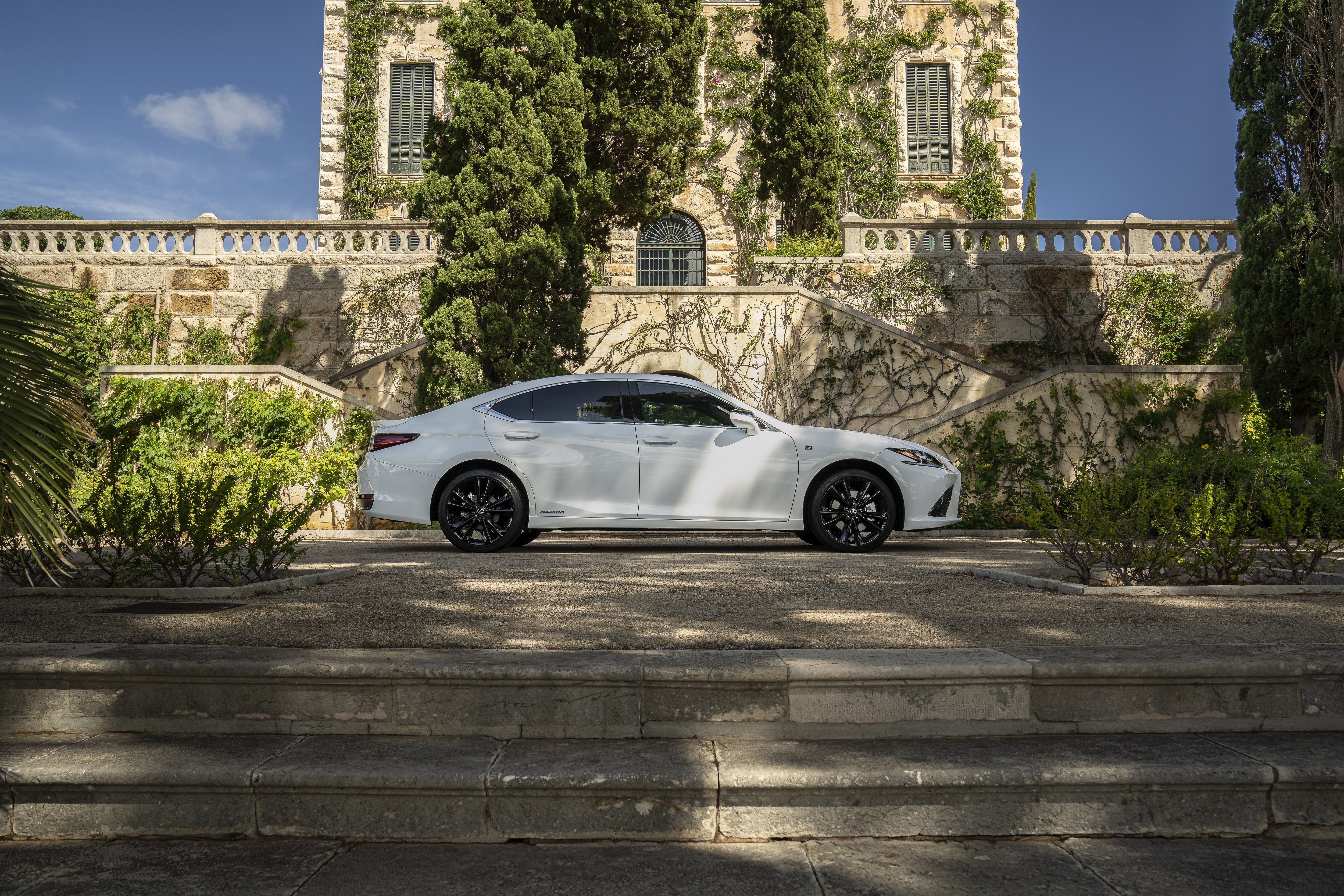 White Lexus ES 300h F SPORT parked near a stone building HD Wallpaper