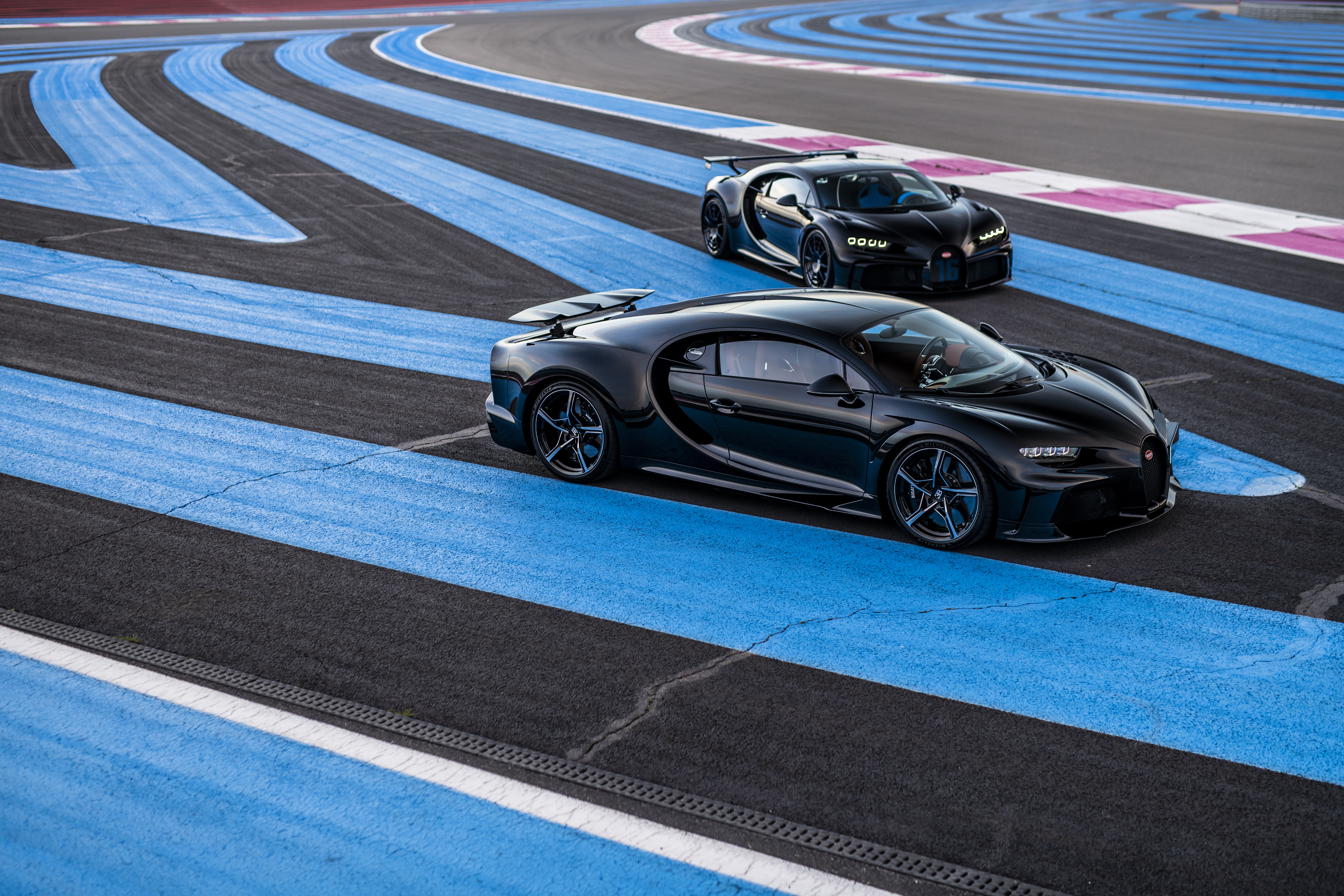 Two black Bugatti Chiron cars on a race track HD Wallpaper