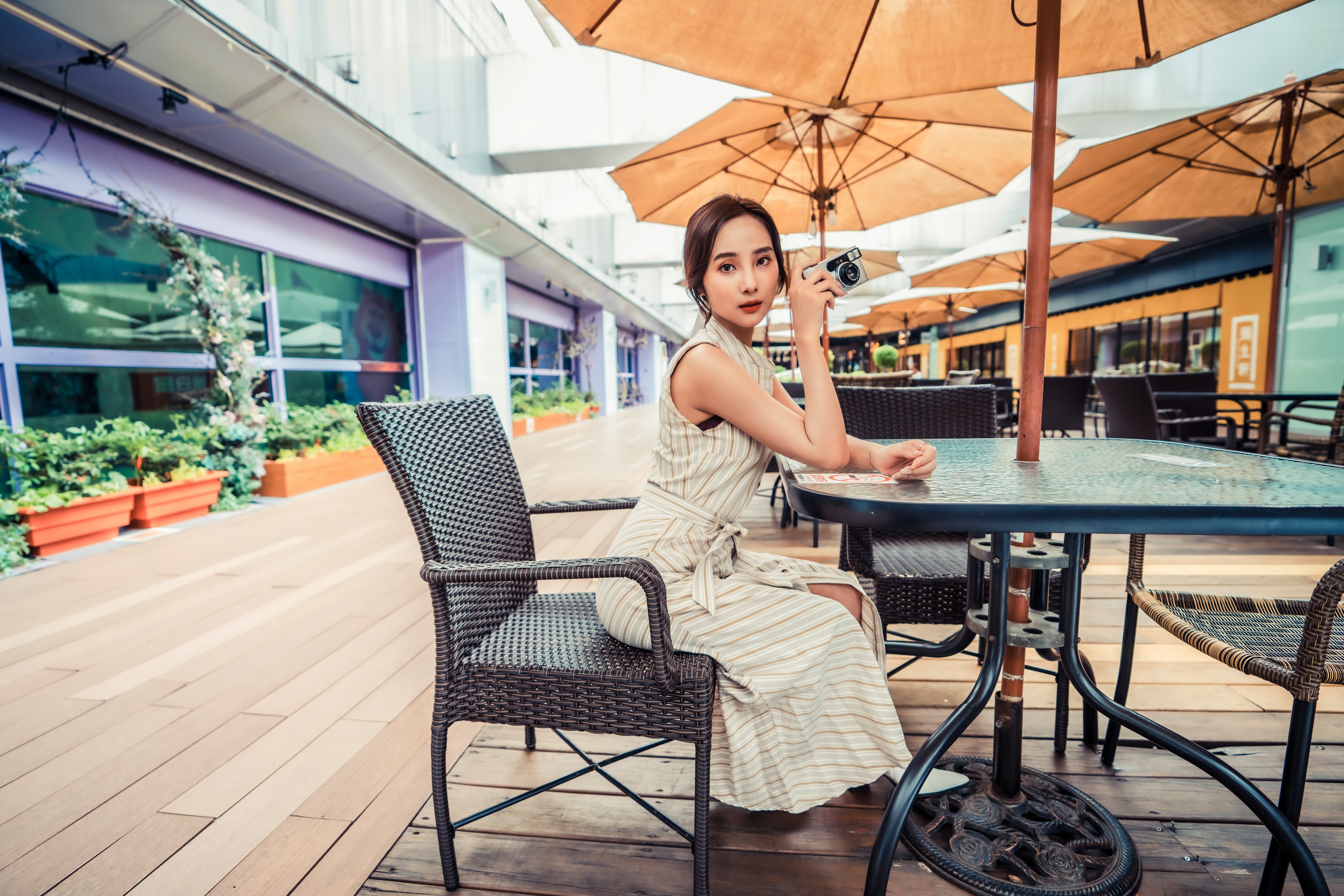Asian woman with camera at outdoor cafe HD Wallpaper