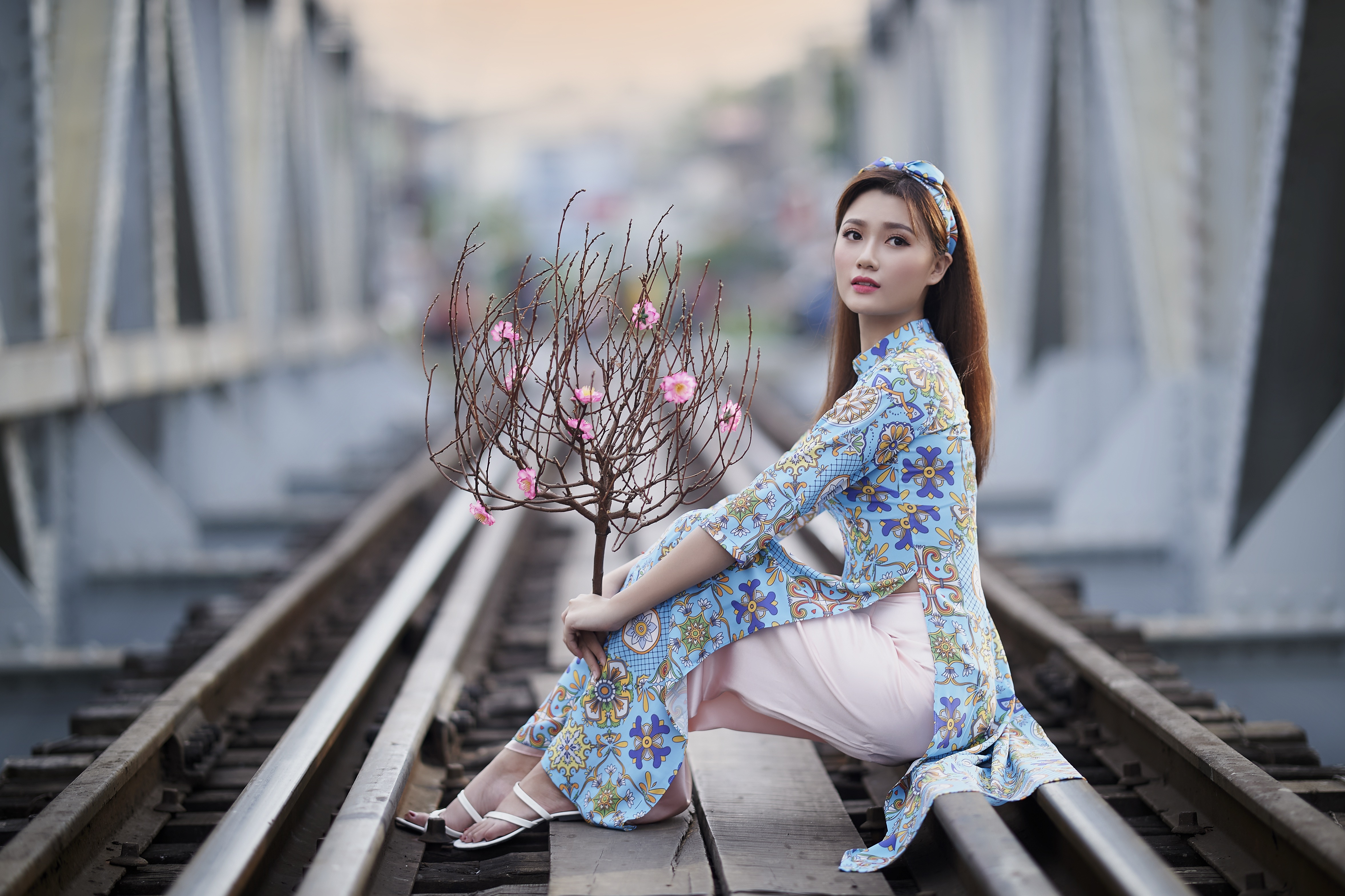Asian woman in traditional dress on train tracks with peach blossoms HD Wallpaper