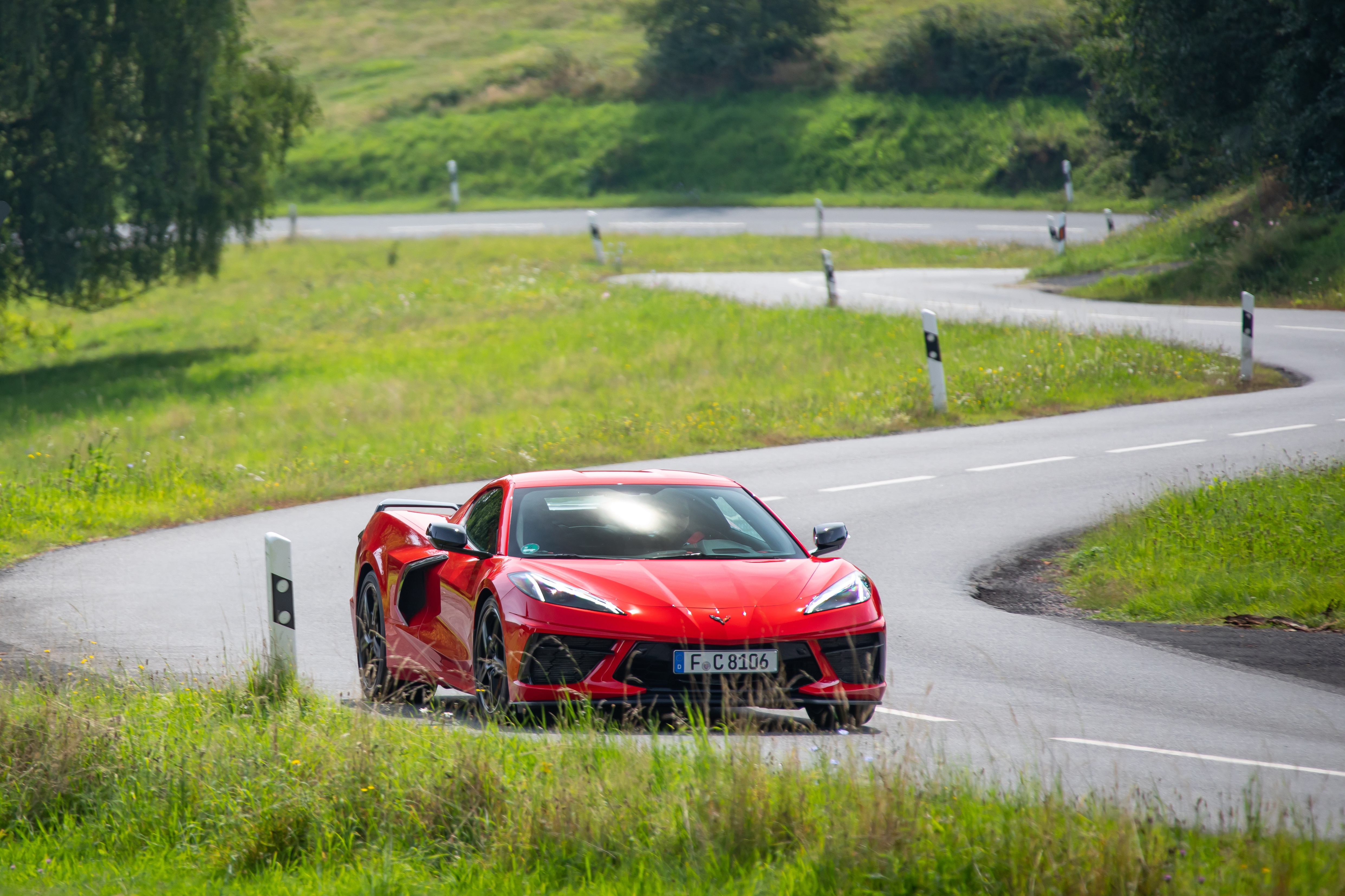 Red Chevrolet Corvette Stingray driving on a winding road HD Wallpaper