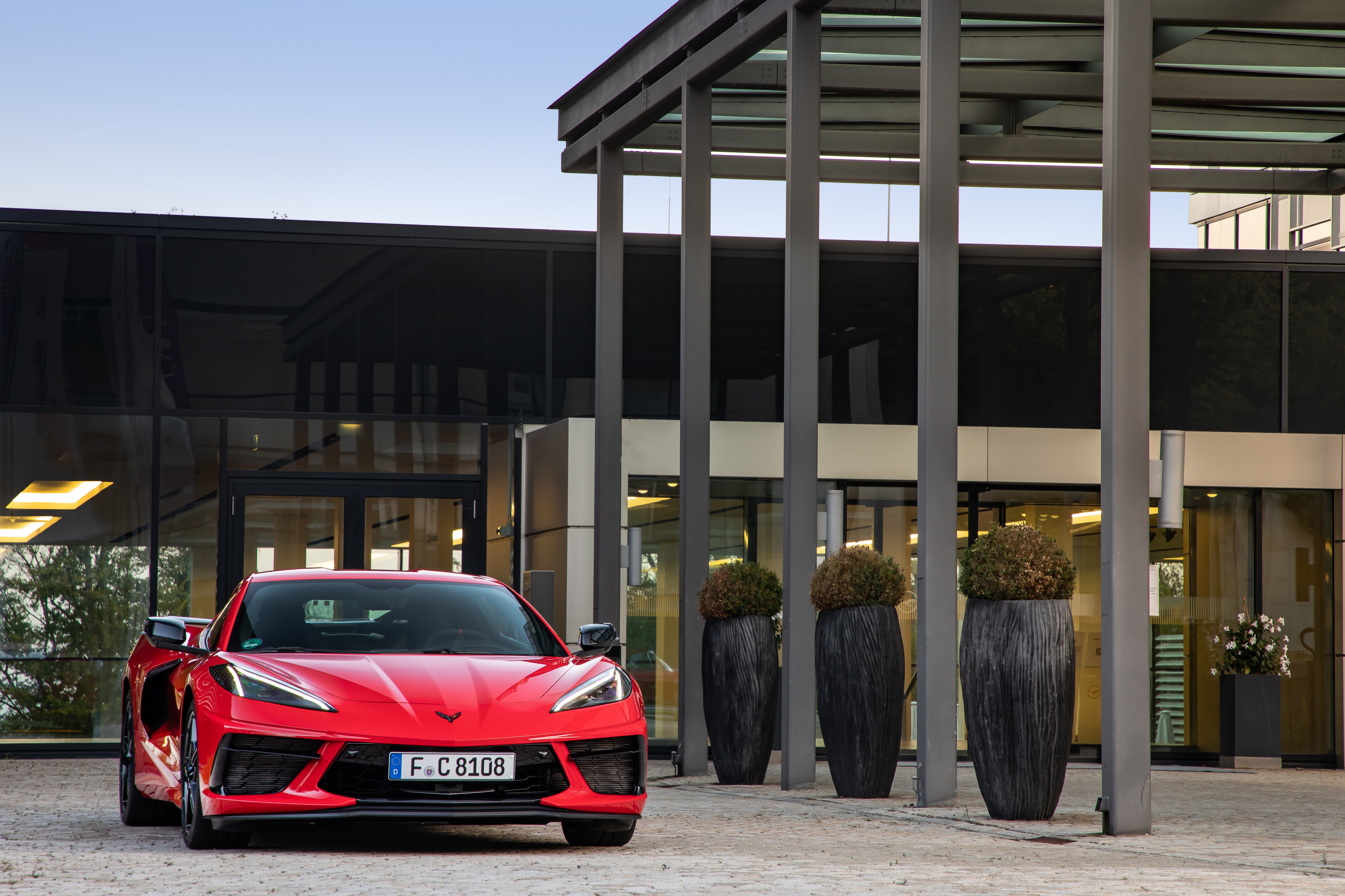 Red Chevrolet Corvette Stingray parked outside building HD Wallpaper