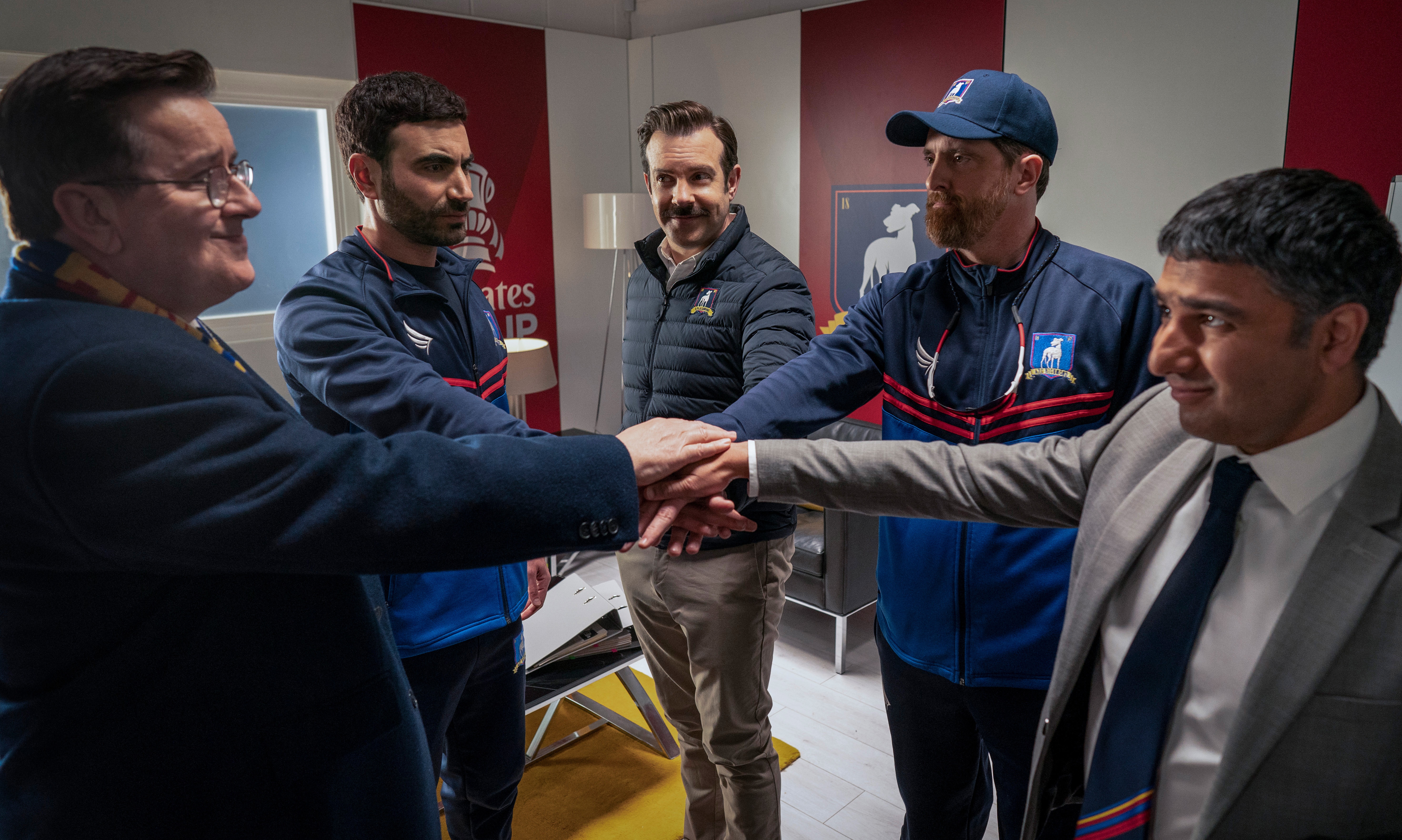 Ted Lasso characters huddle in a locker room HD Wallpaper
