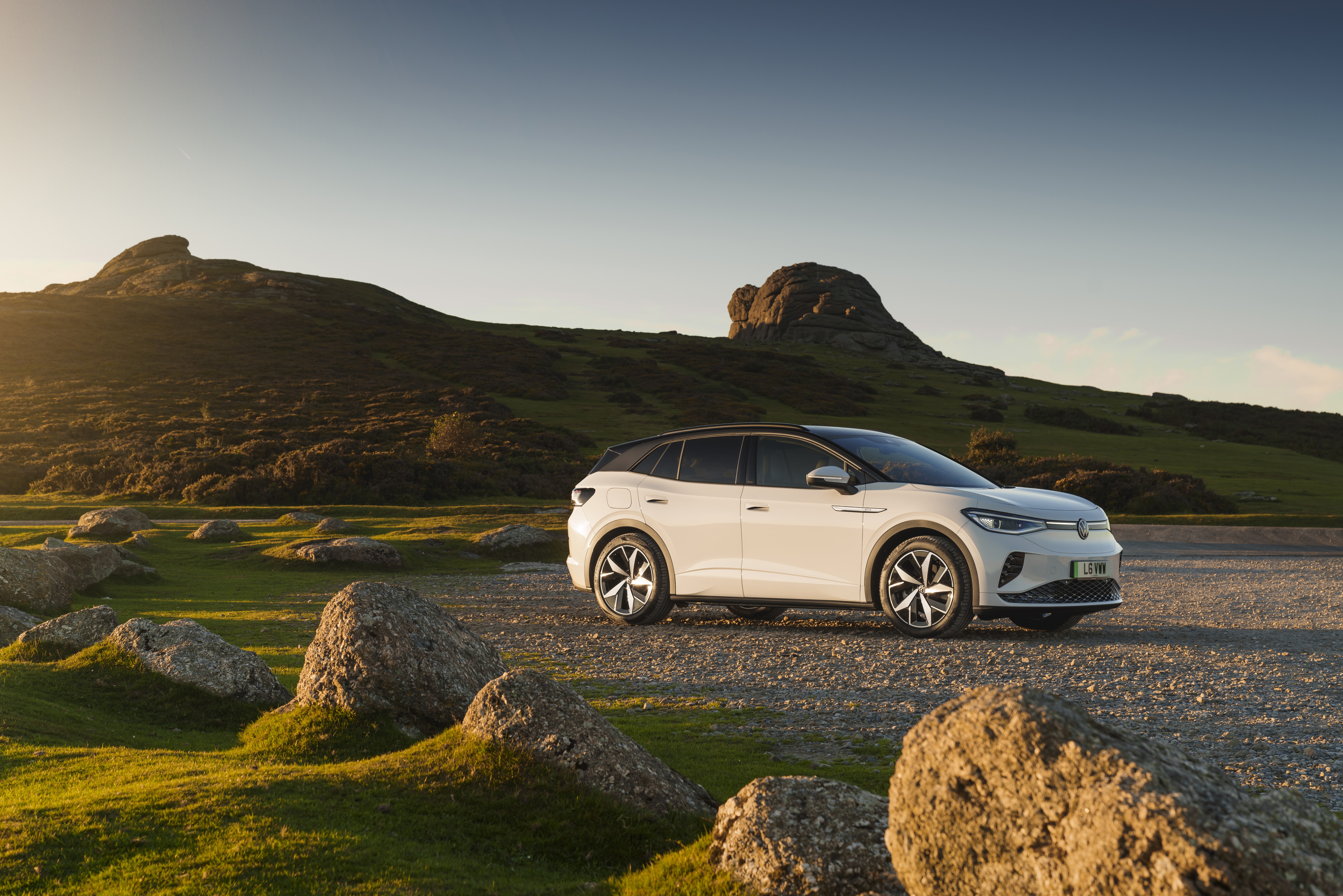 White Volkswagen ID.4 Electric Car on Rocky Hillside HD Wallpaper