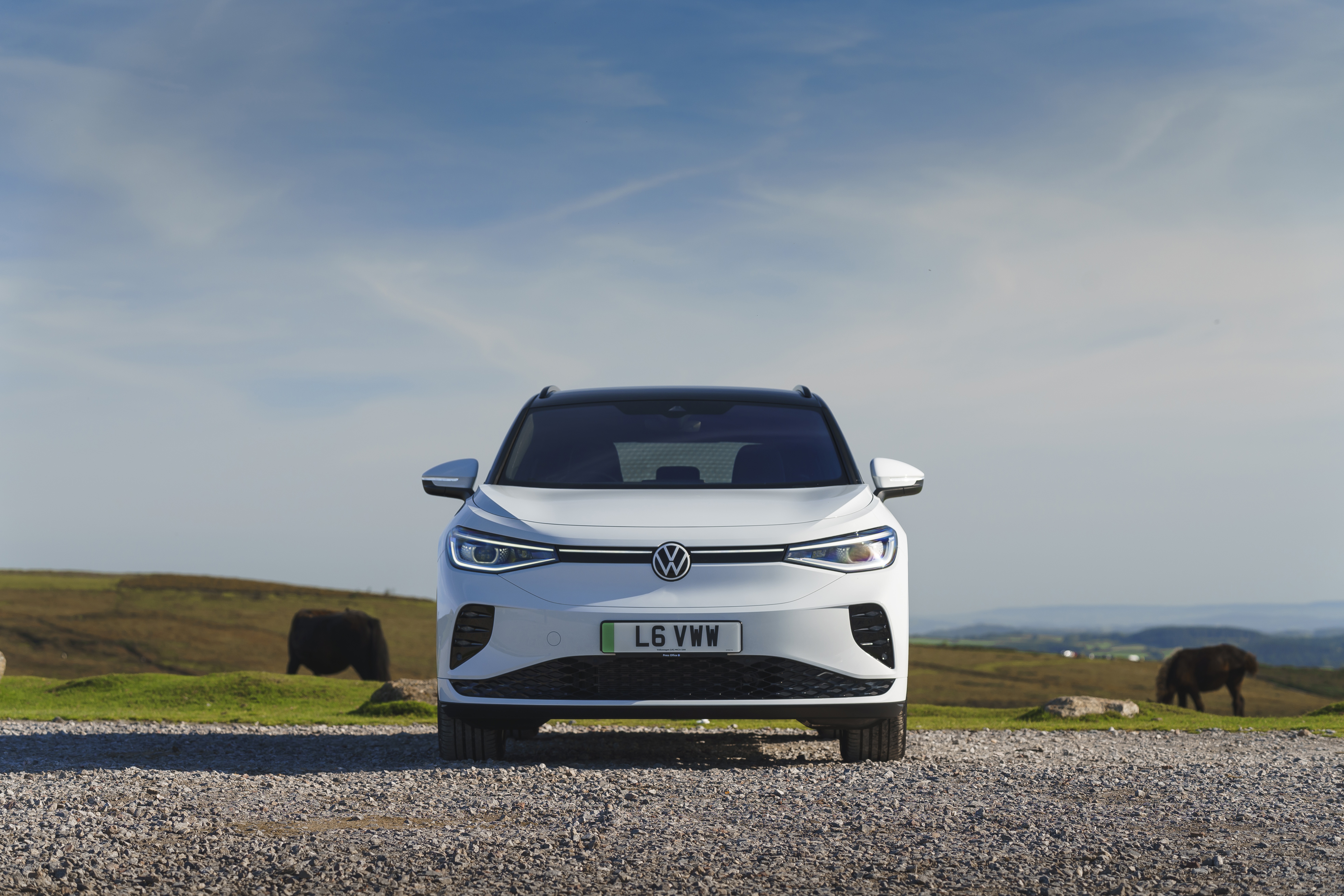 White Volkswagen ID.4 electric car on a gravel road HD Wallpaper
