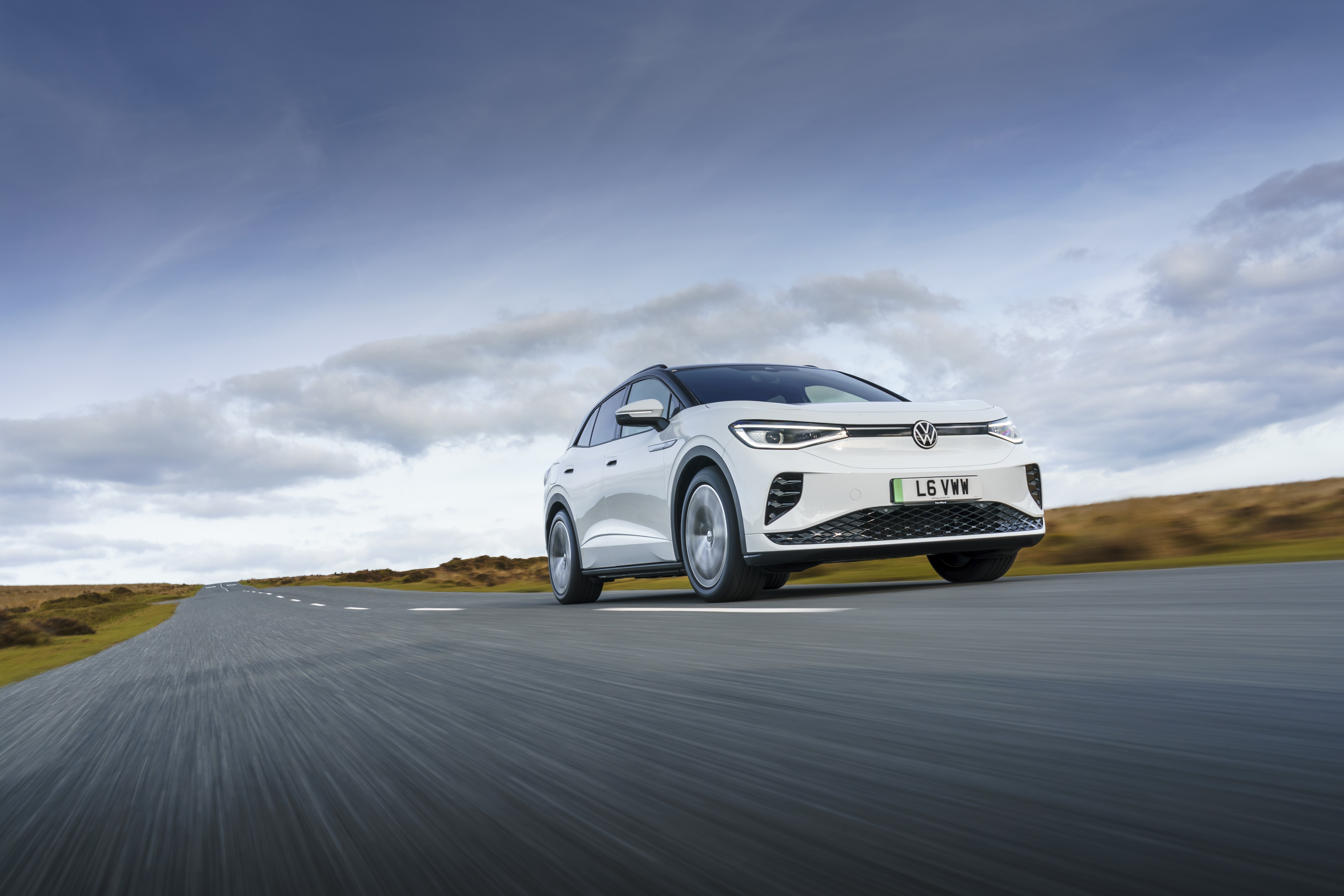 White Volkswagen ID.4 driving on a road HD Wallpaper