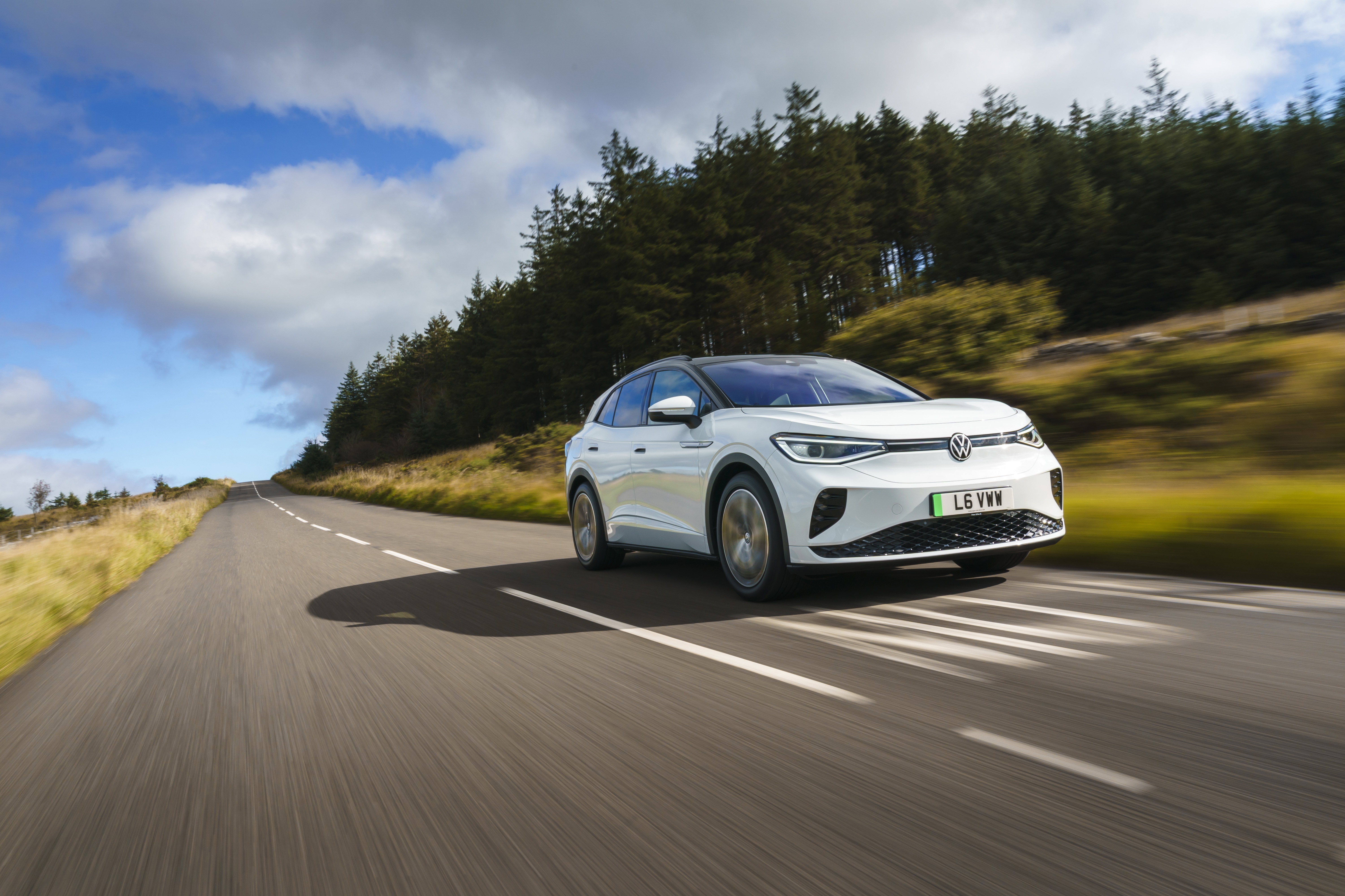 White Volkswagen ID.4 electric car driving on a road HD Wallpaper