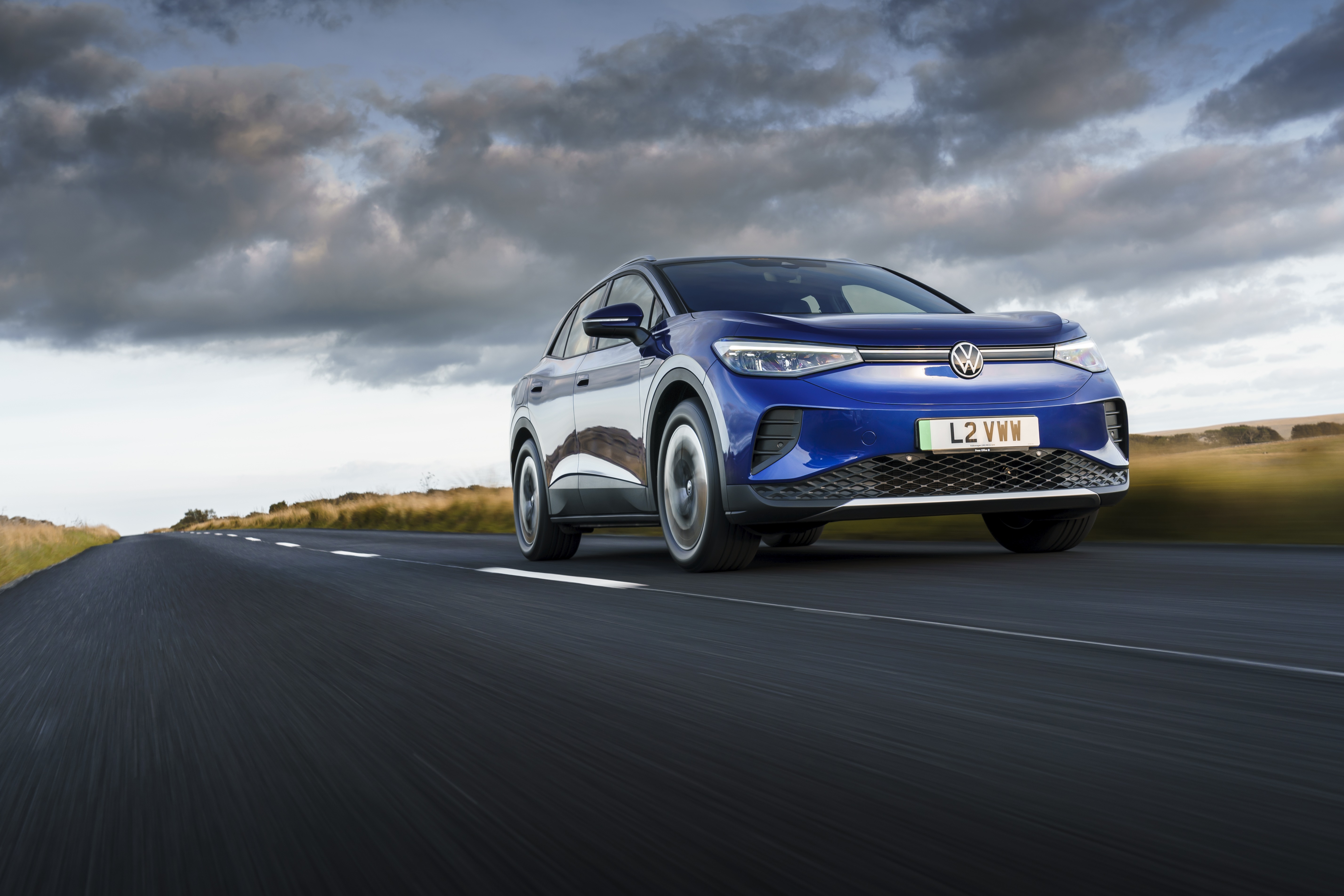 Blue Volkswagen ID.4 electric car driving on a road HD Wallpaper