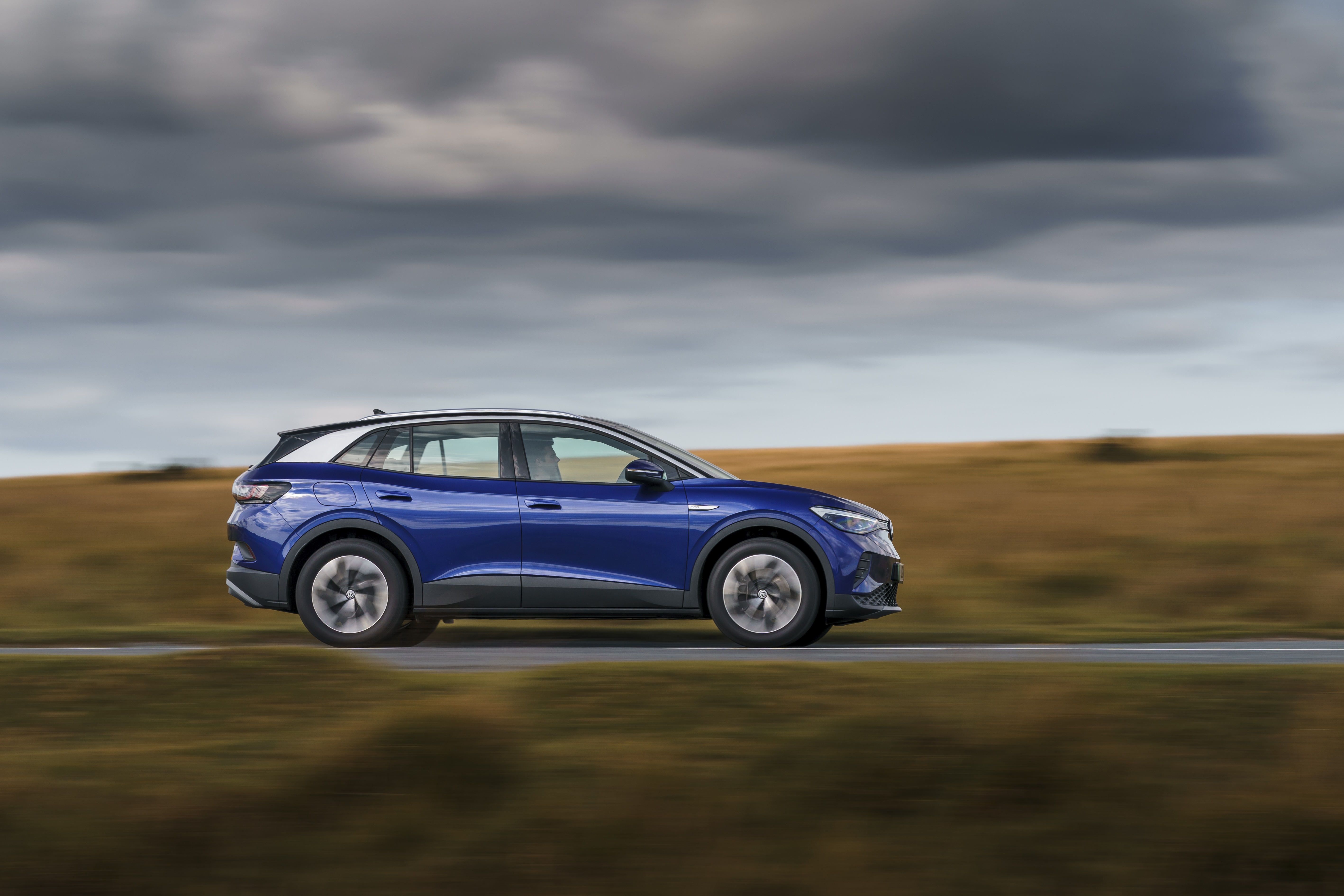 Blue Volkswagen ID.4 electric car driving on a road HD Wallpaper