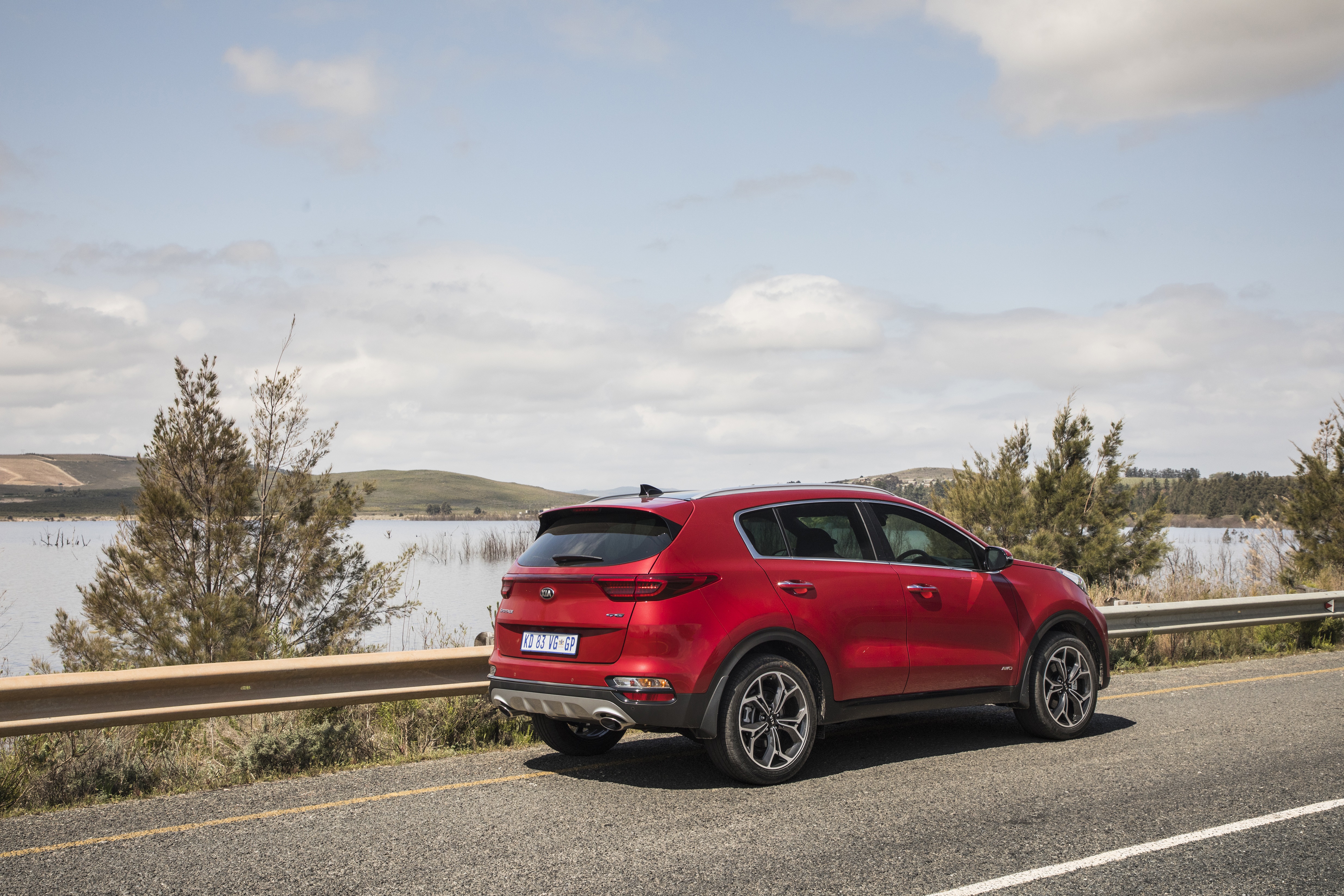 Red Kia Sportage SUV parked by a lake HD Wallpaper