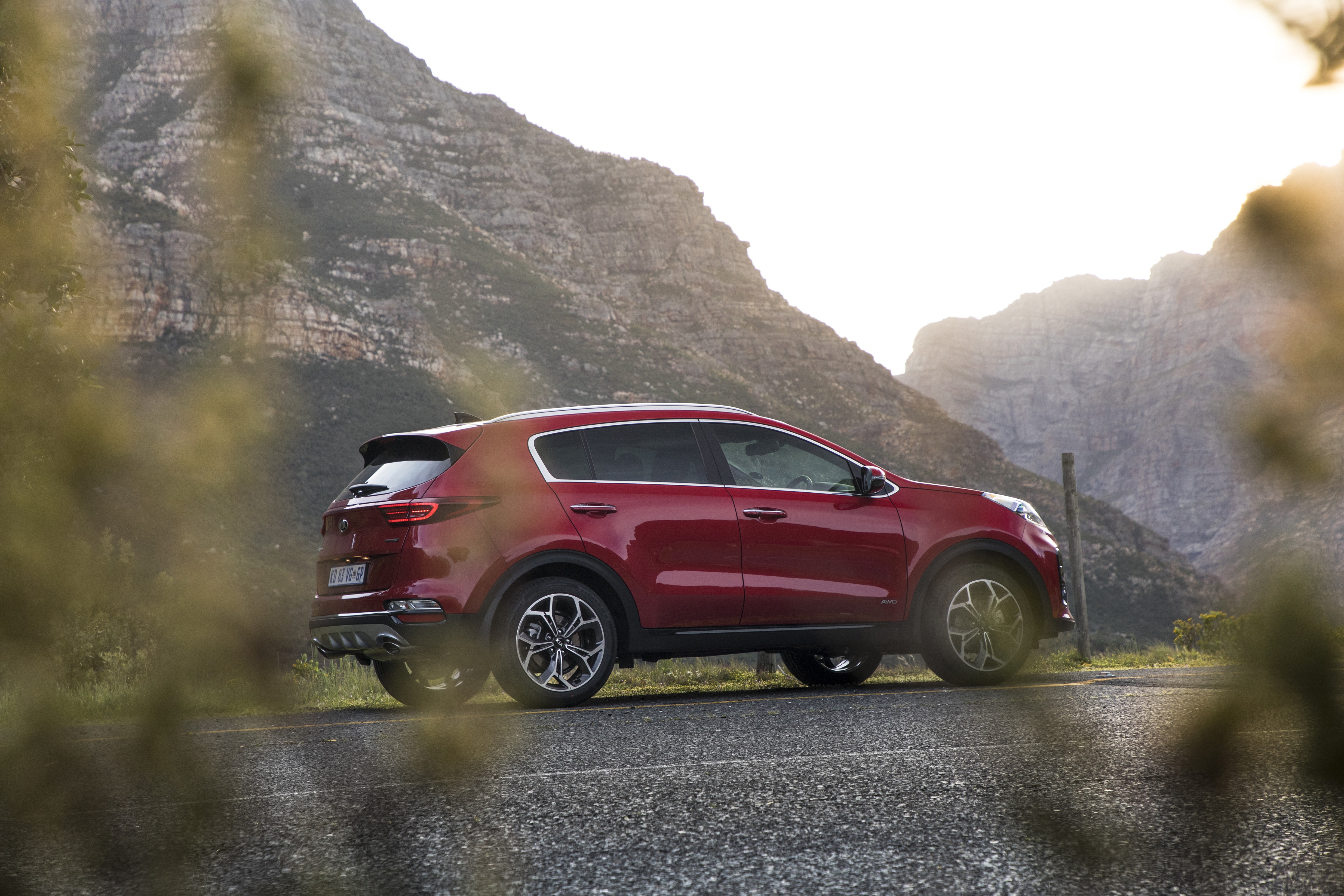 Red Kia Sportage SUV on a mountain road HD Wallpaper