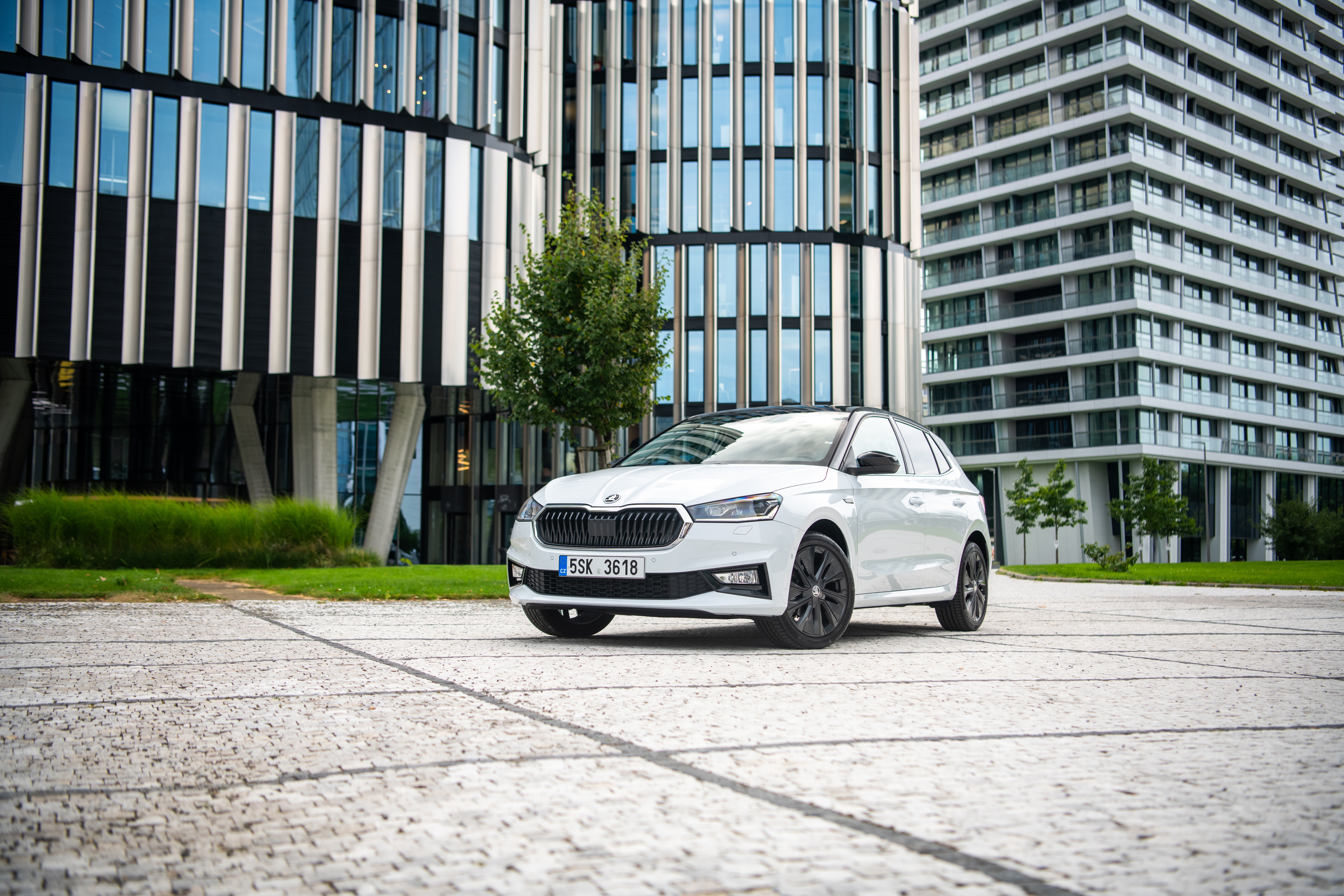 White Skoda Fabia parked in front of modern buildings HD Wallpaper