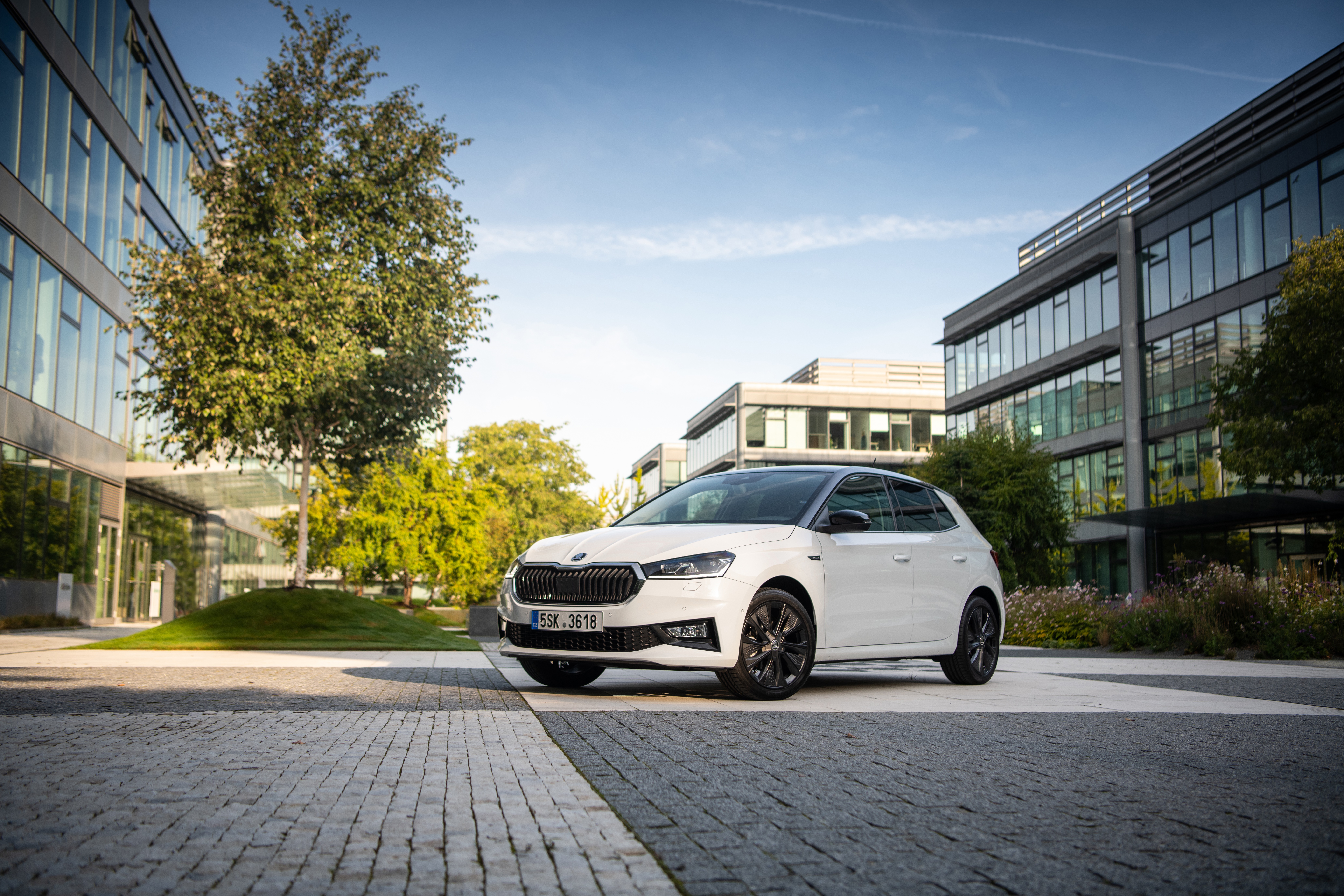 White Skoda Fabia parked outside modern office buildings HD Wallpaper