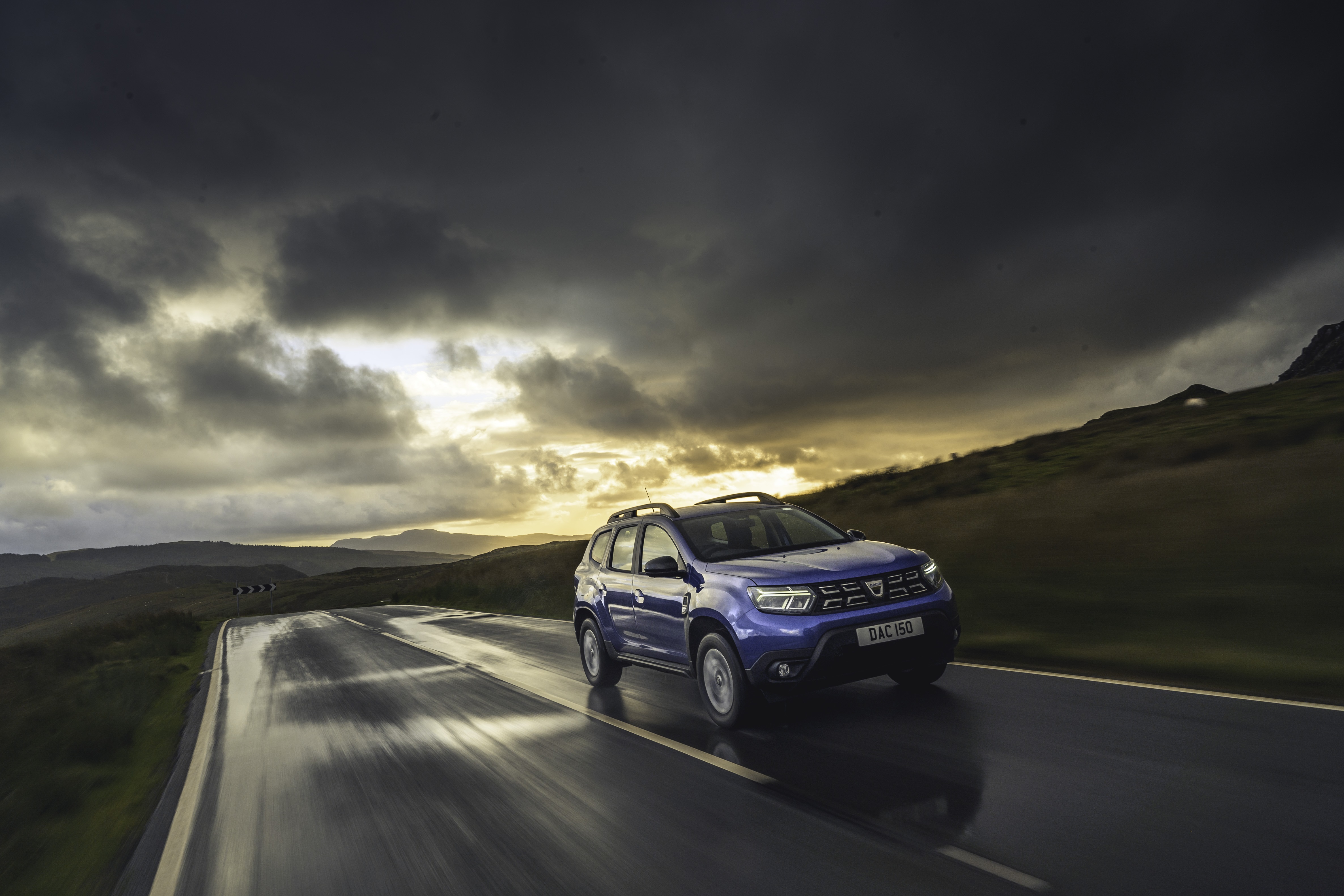 Blue Dacia Duster driving on a wet road HD Wallpaper