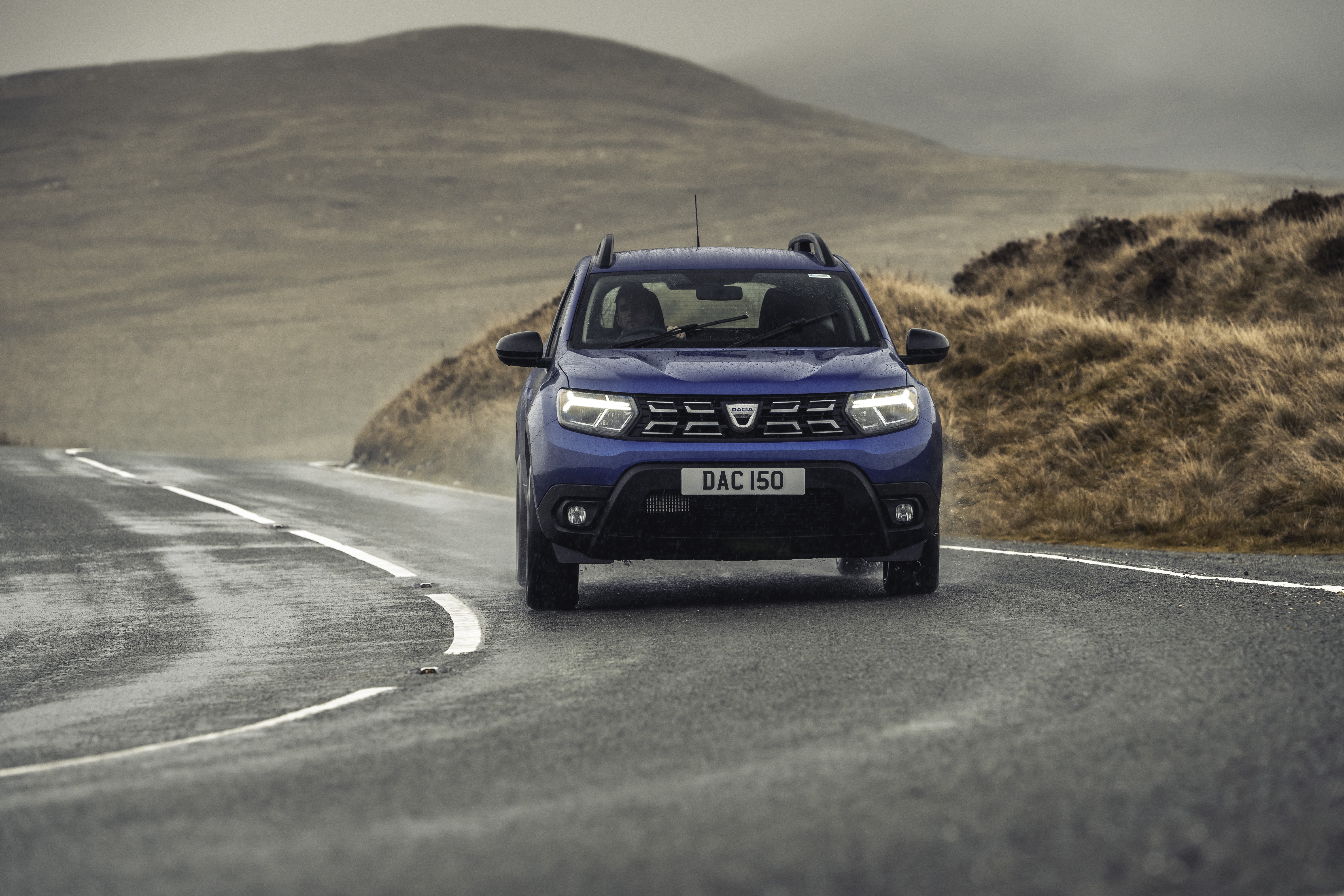 Blue Dacia Duster driving on a wet road HD Wallpaper