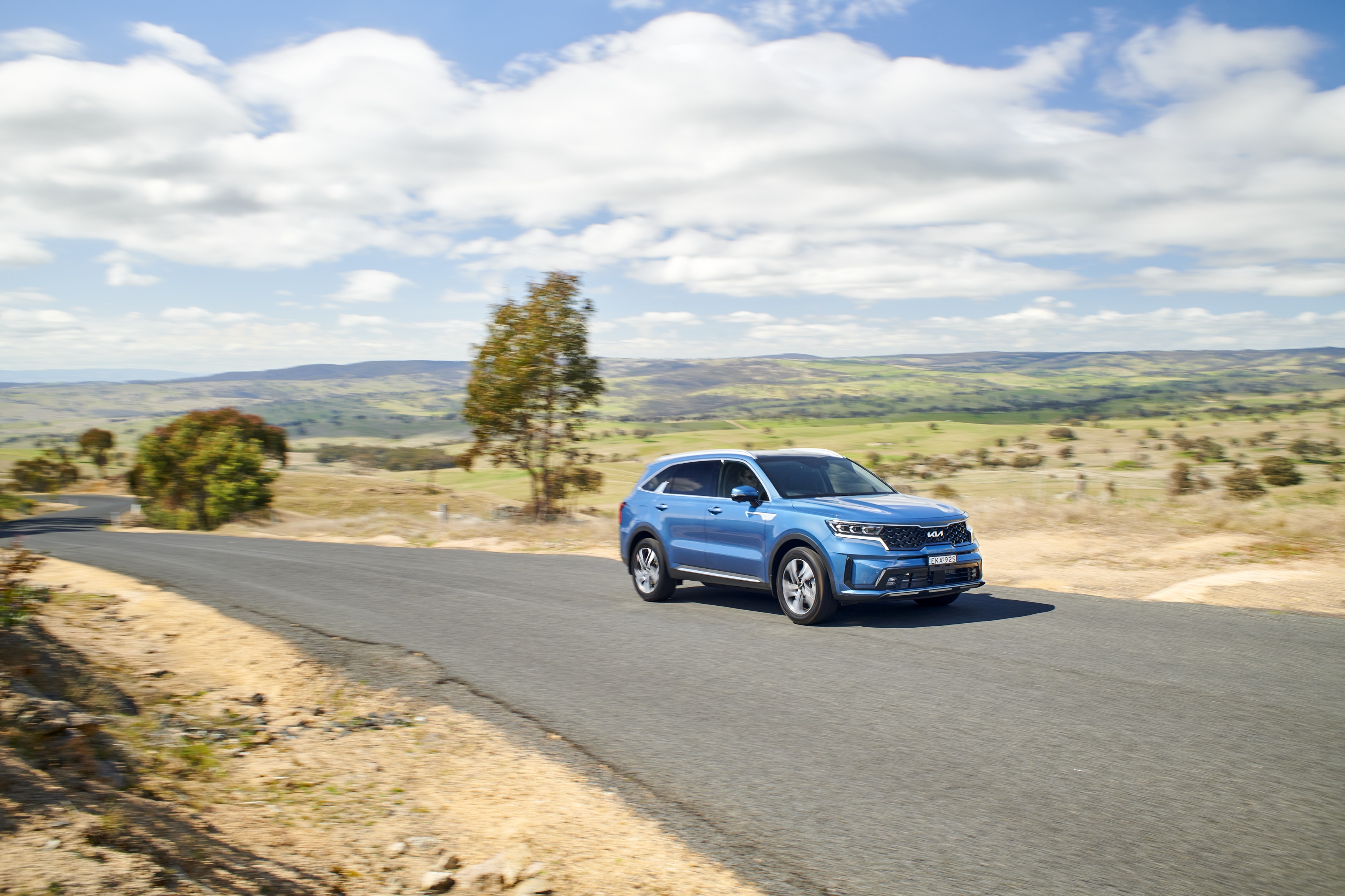 Blue Kia Sorento Plug-in Hybrid SUV on a country road HD Wallpaper