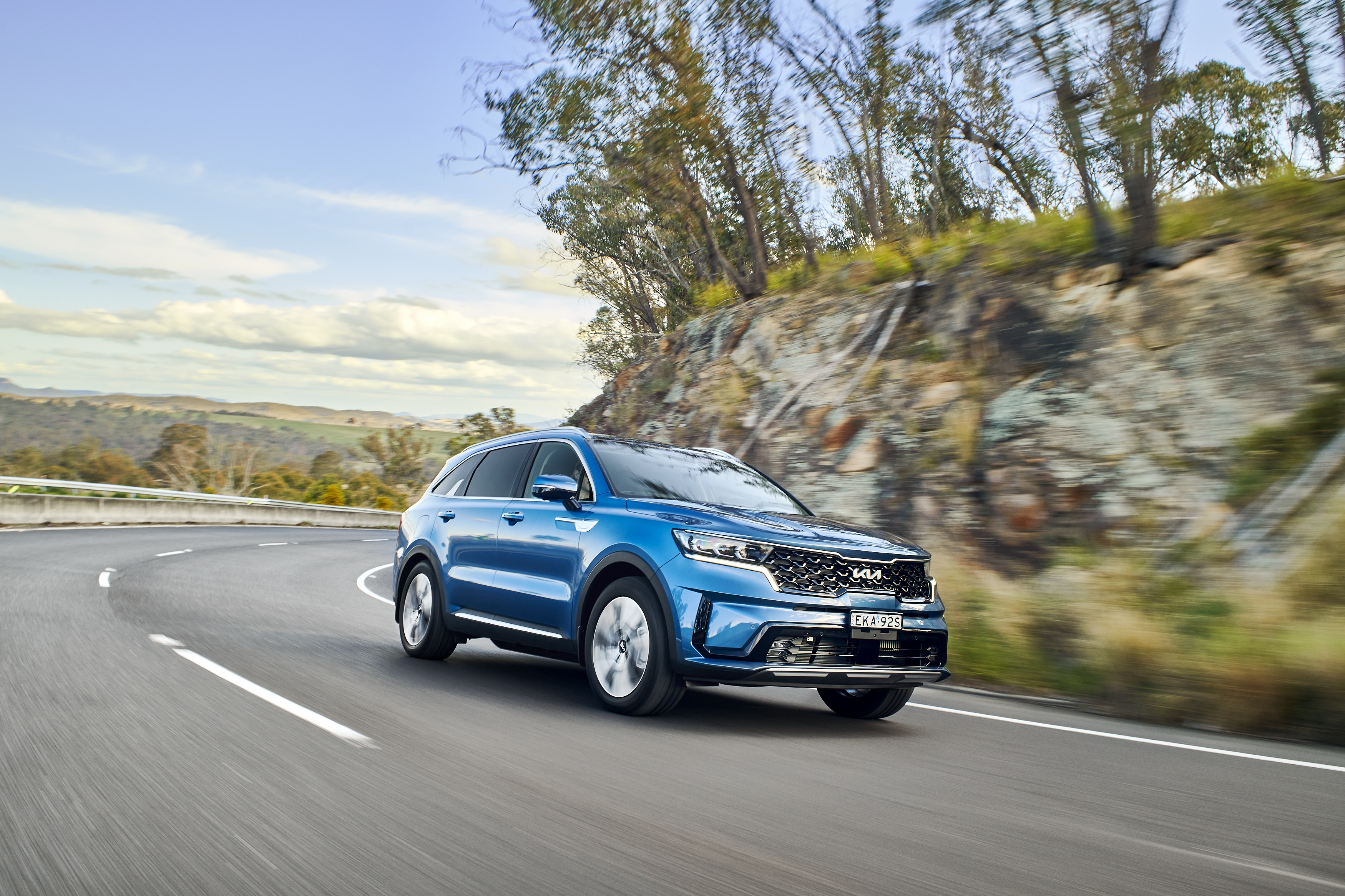 Blue Kia Sorento Plug-in Hybrid SUV driving on a road HD Wallpaper