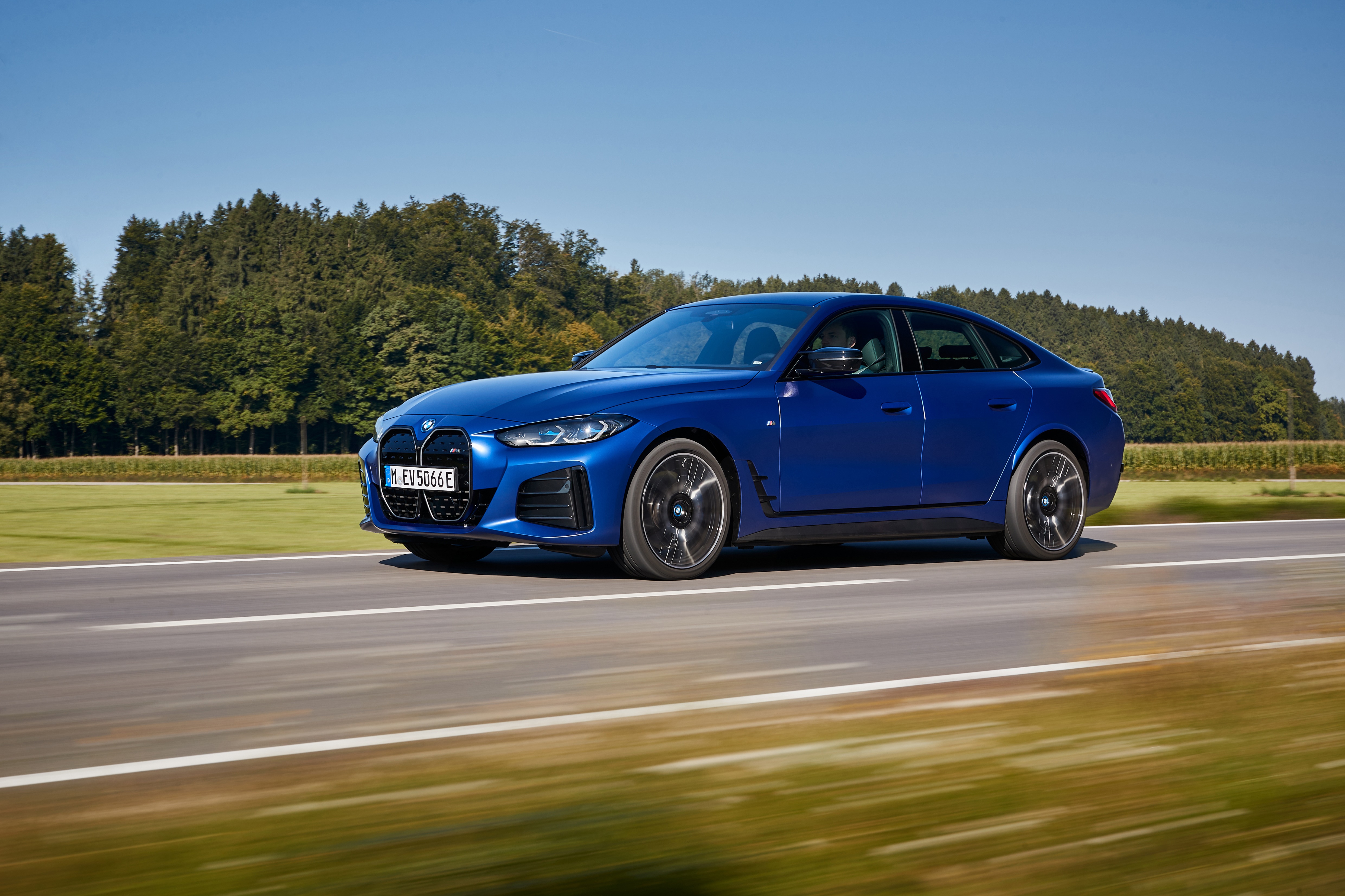 Blue BMW i4 M50 driving on a road HD Wallpaper