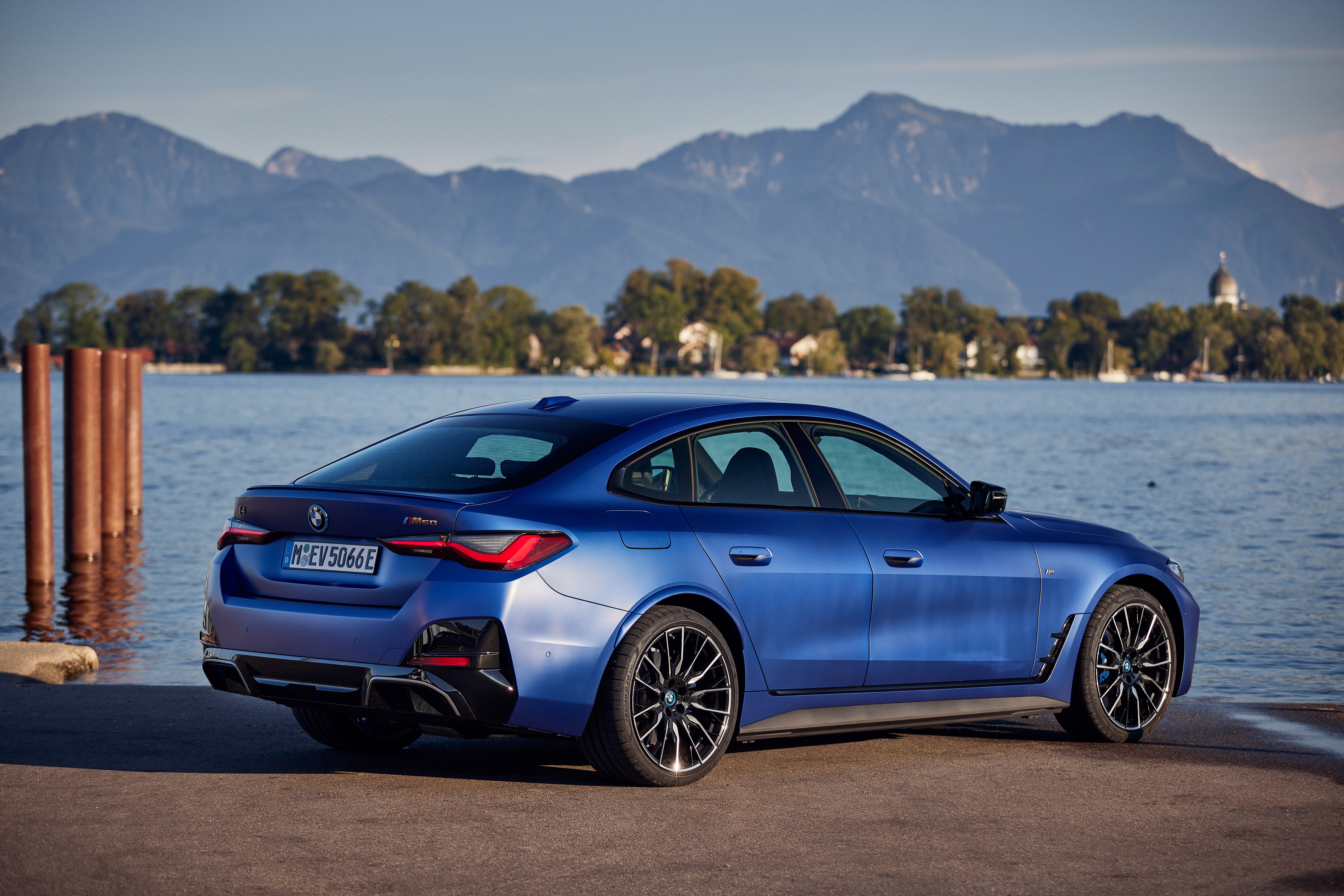 Blue BMW i4 M50 parked by a lake with mountains HD Wallpaper