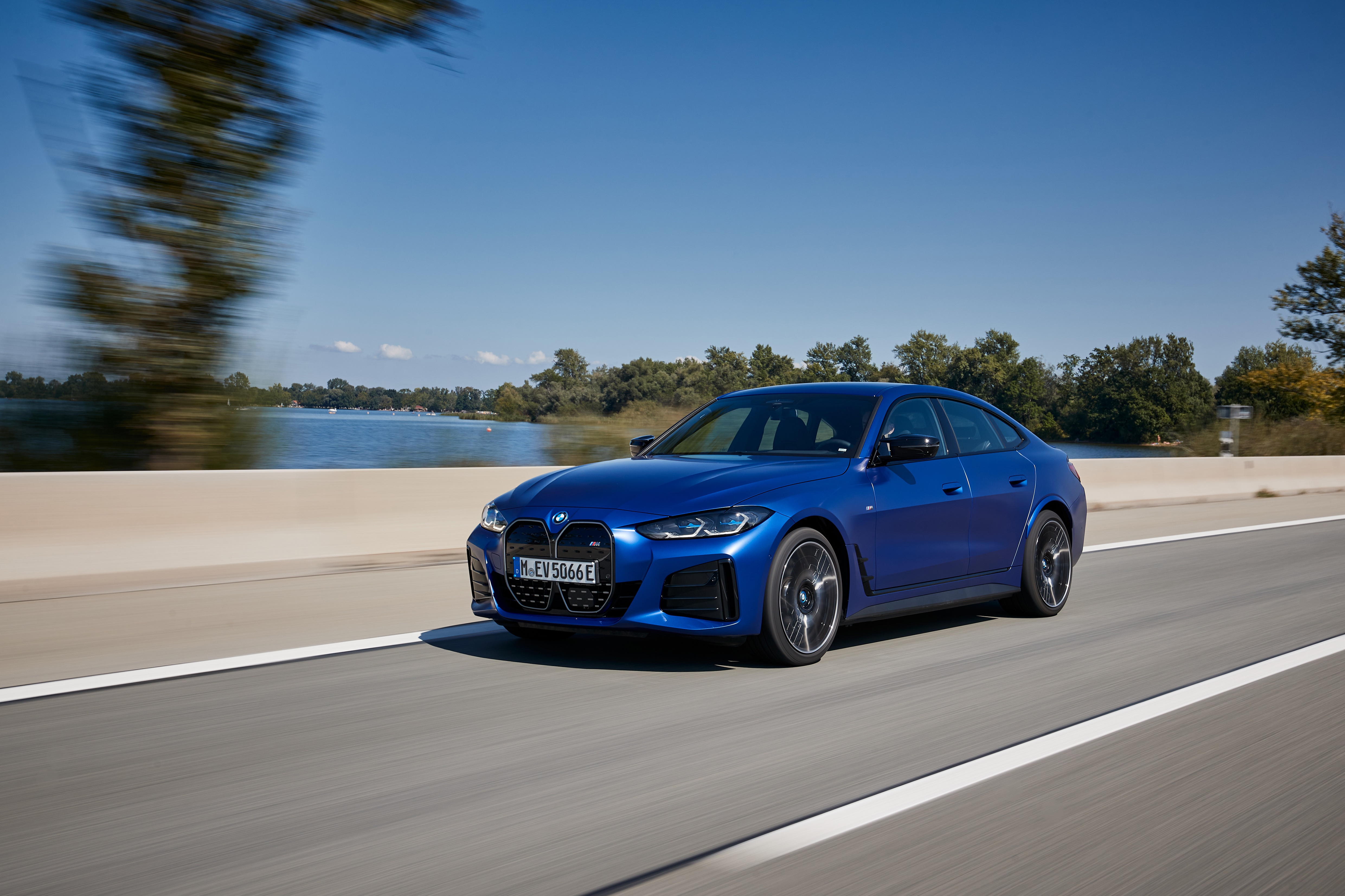 Blue BMW i4 M50 driving on a road HD Wallpaper