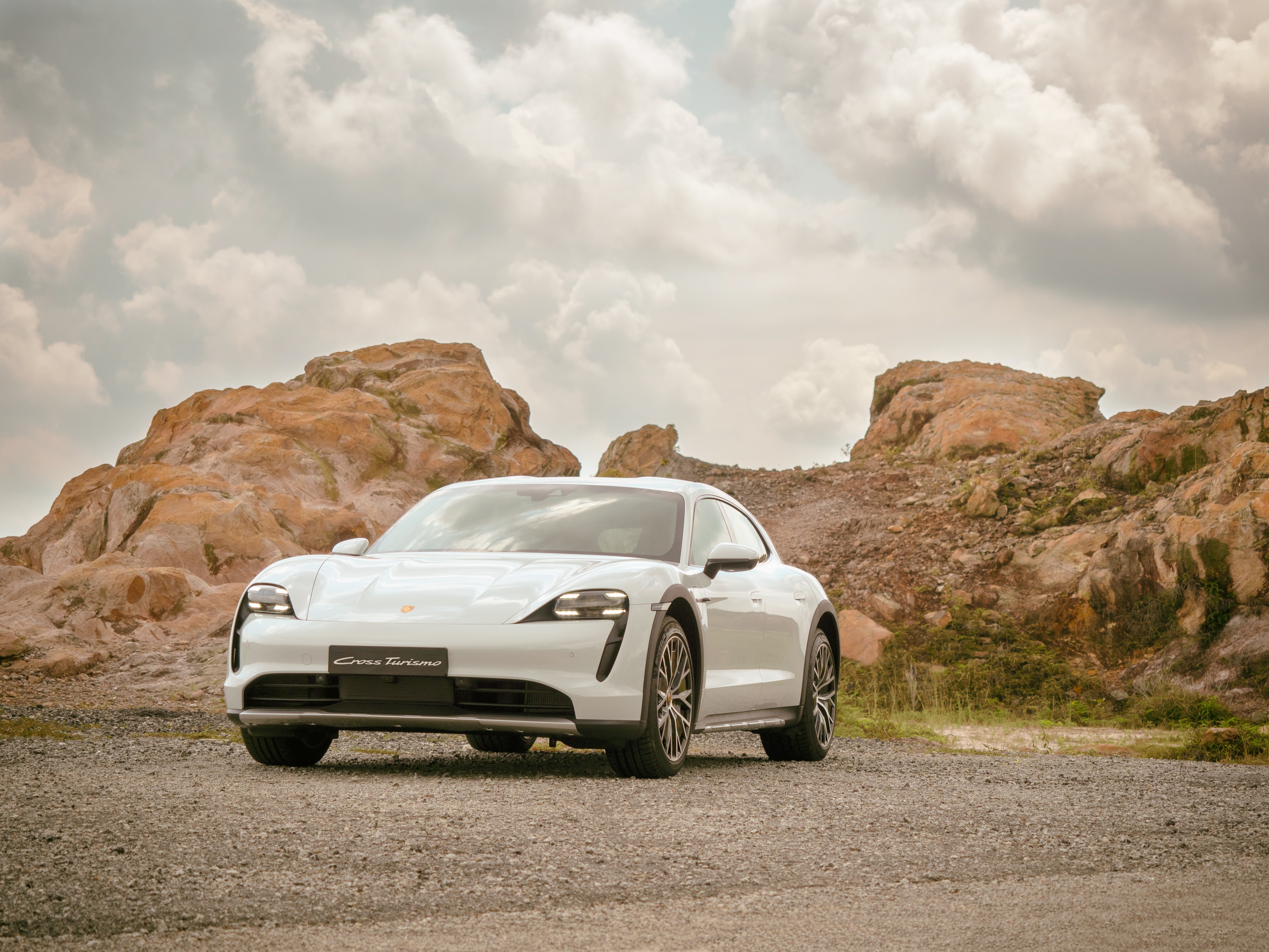 White Porsche Taycan 4S Cross Turismo in rocky landscape HD Wallpaper