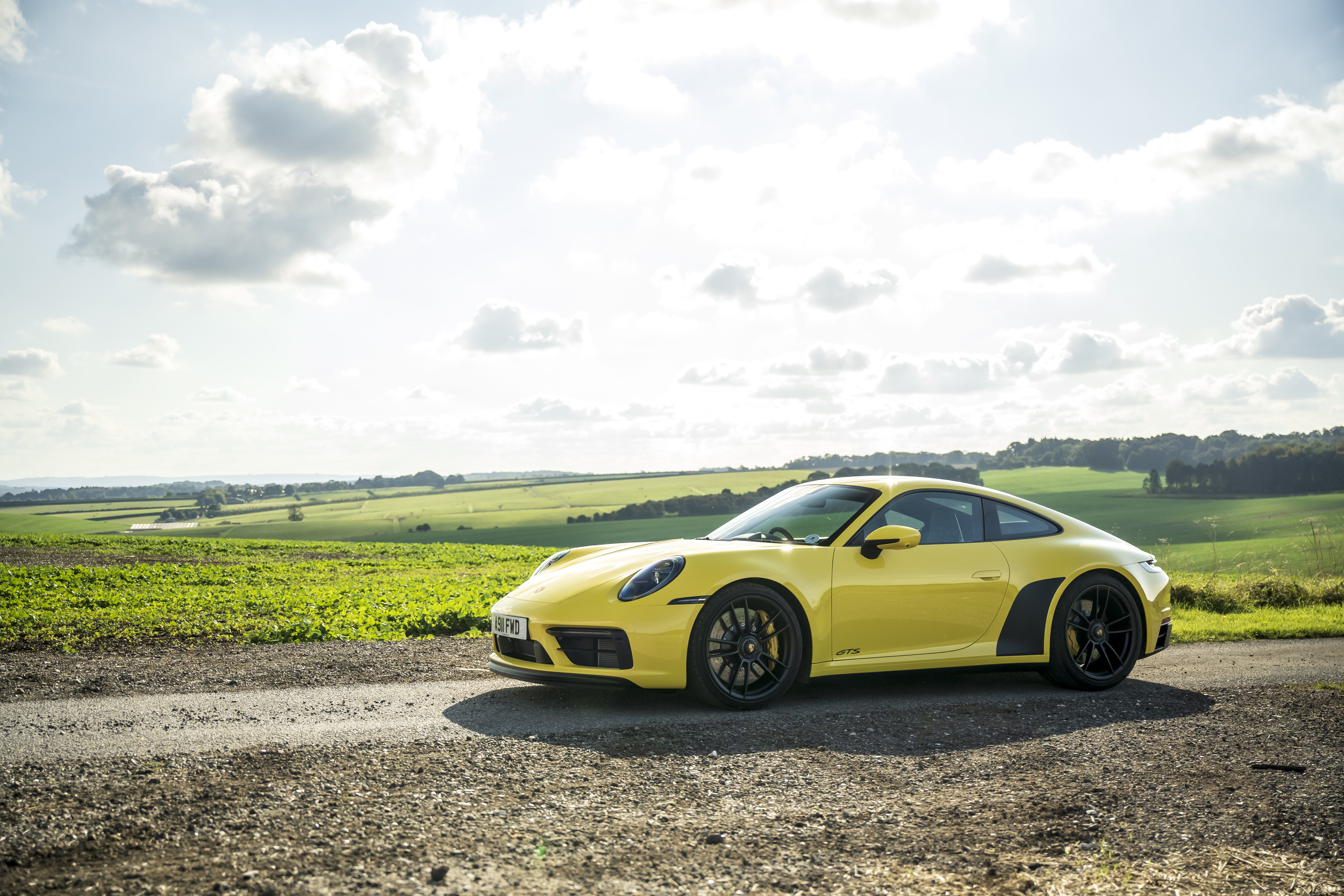 Yellow Porsche 911 Carrera GTS on a rural road HD Wallpaper