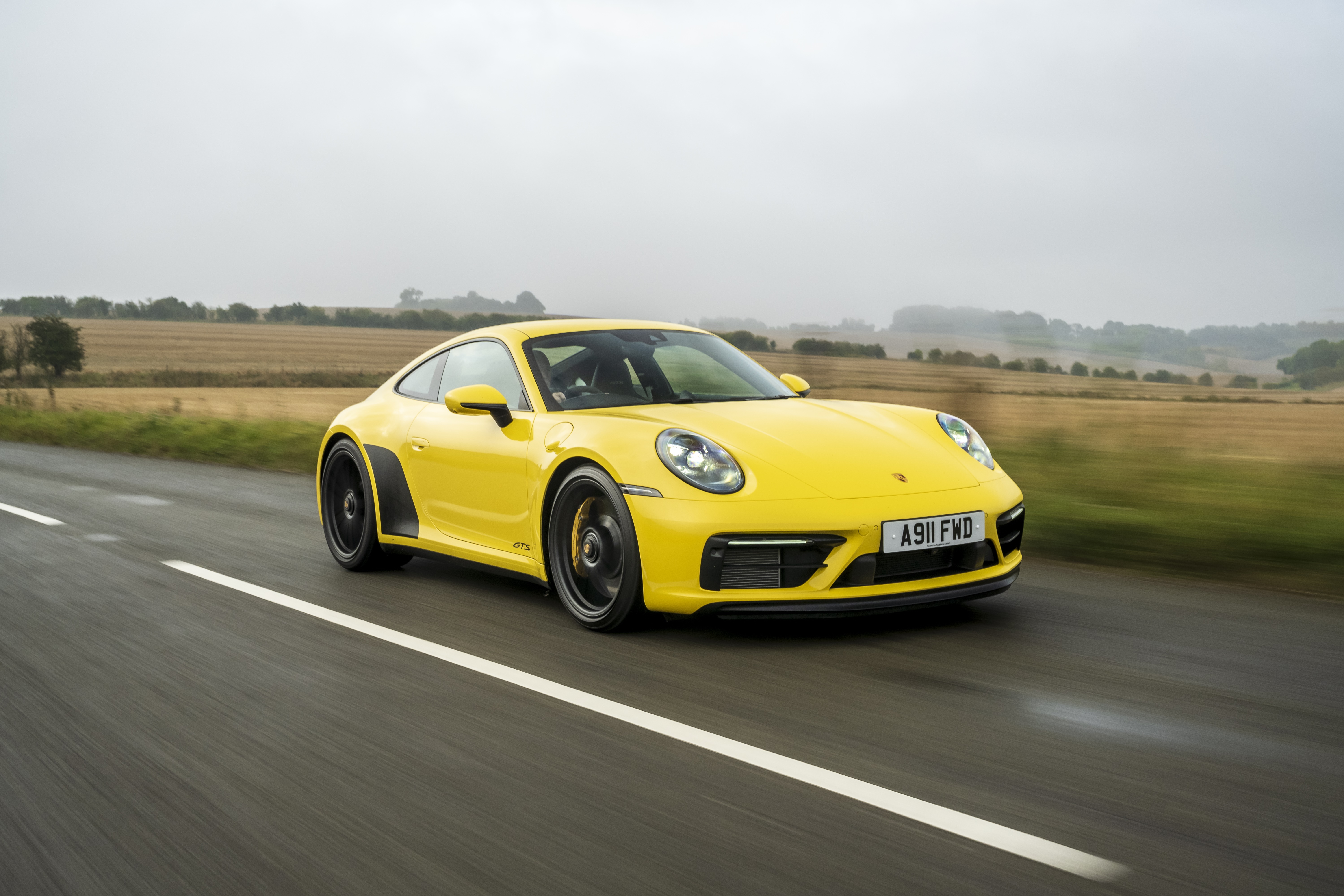 Yellow Porsche 911 Carrera GTS driving on road HD Wallpaper