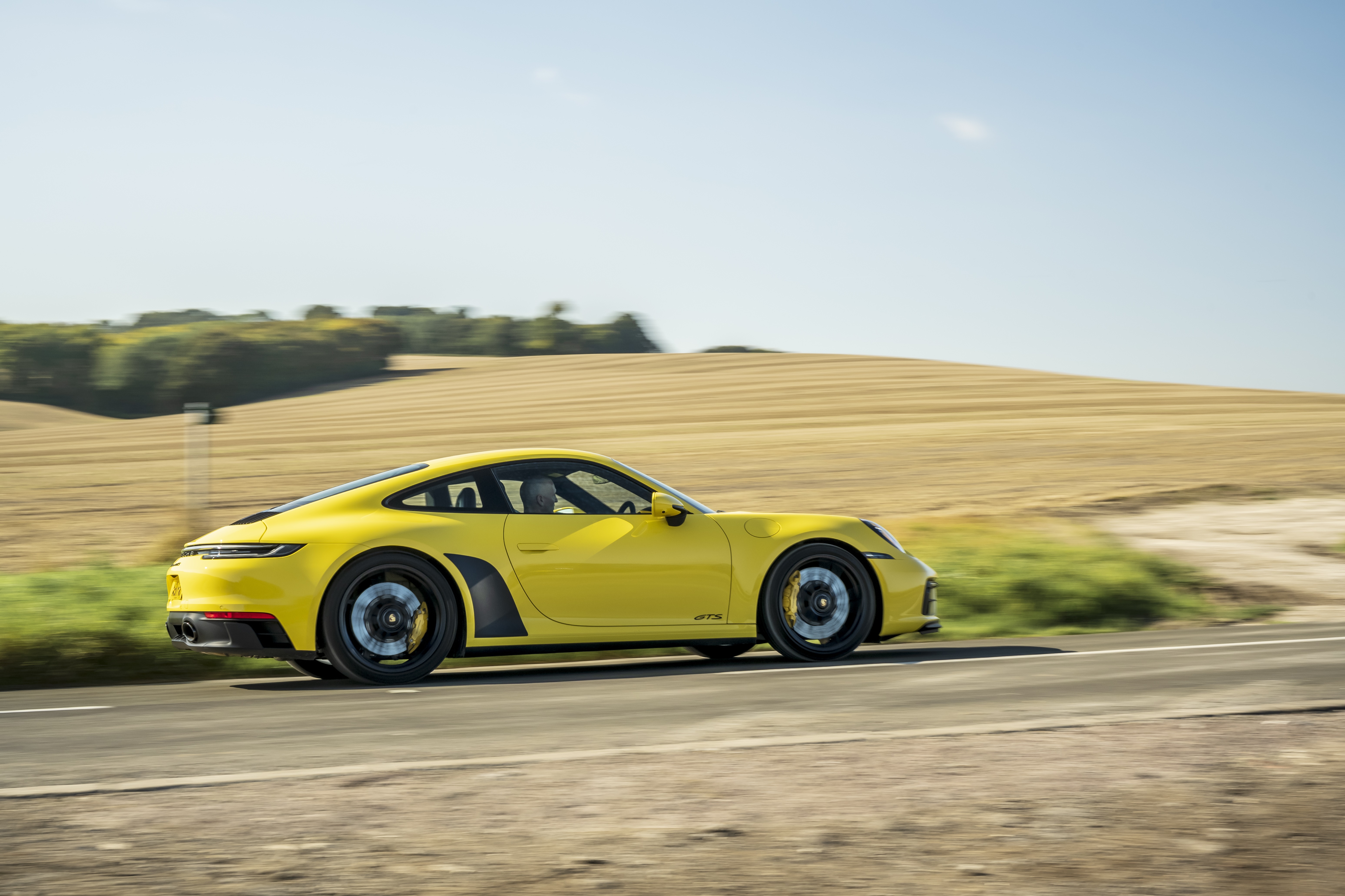 Yellow Porsche 911 Carrera GTS driving on a road HD Wallpaper