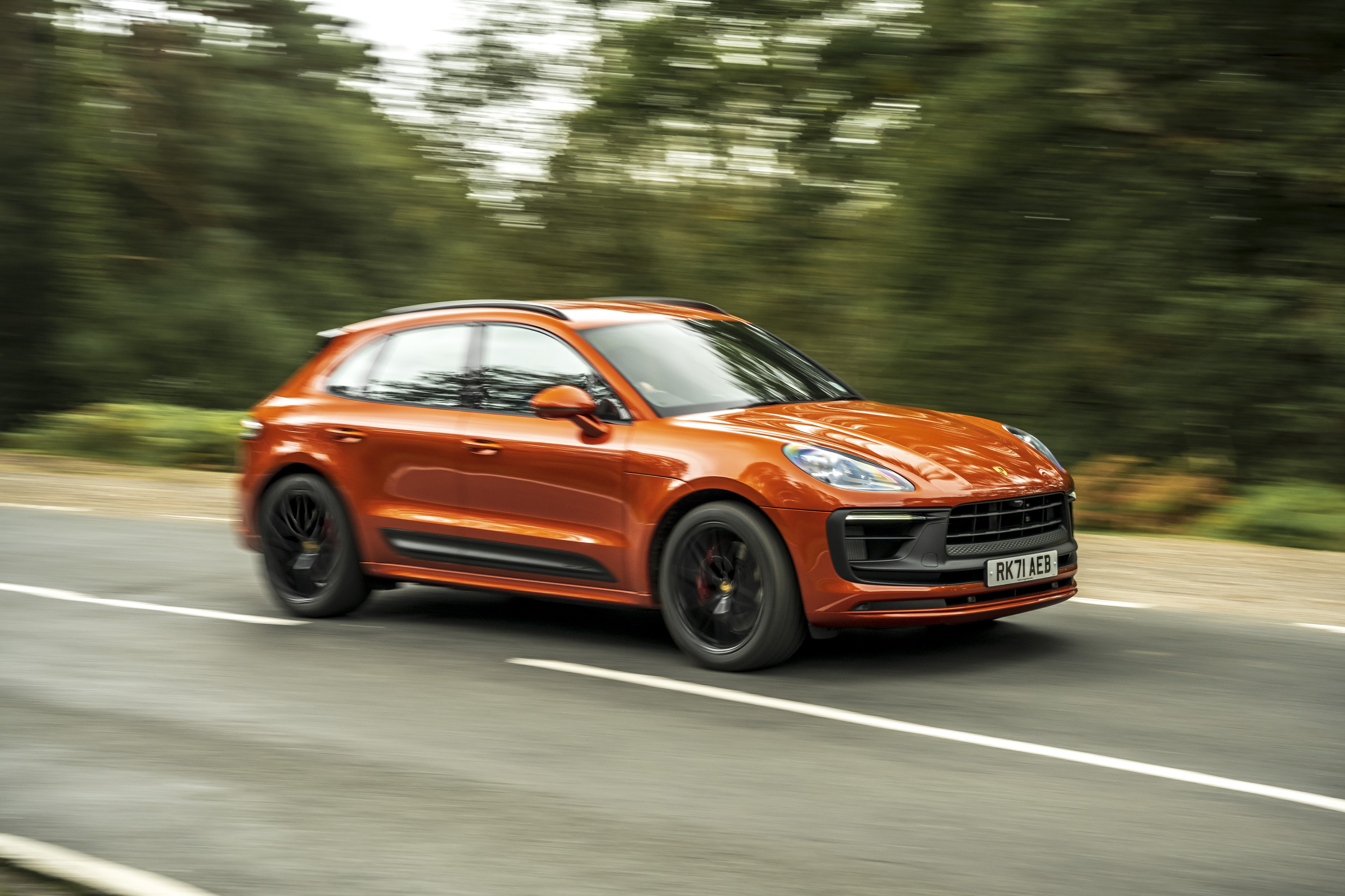 Orange Porsche Macan GTS SUV driving on a road HD Wallpaper