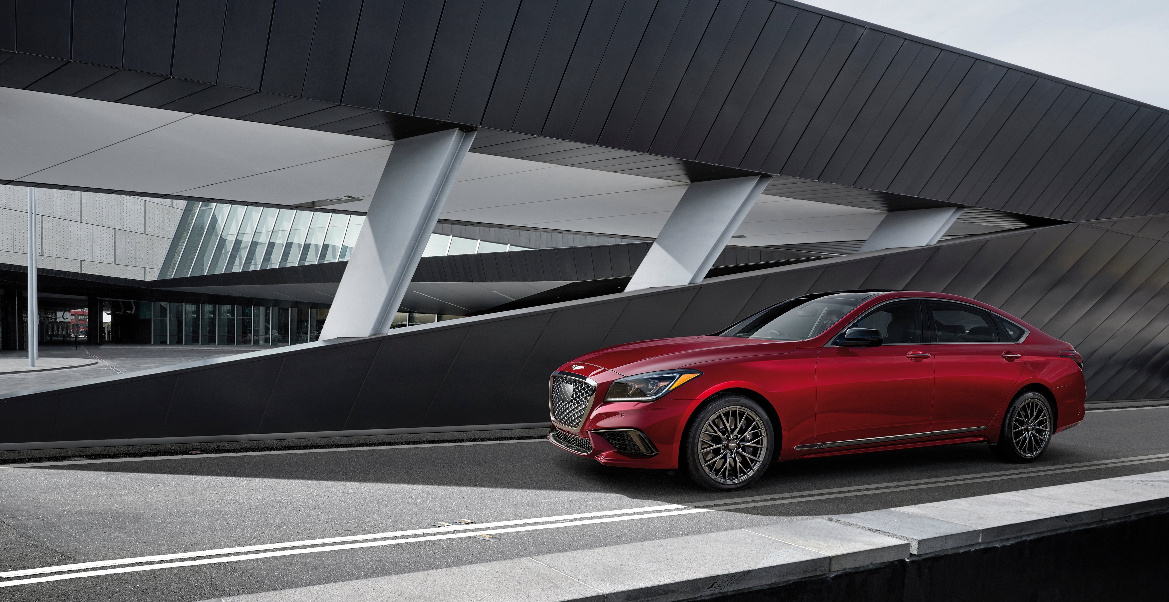 Red Genesis G80 Sedan parked near modern architecture HD Wallpaper