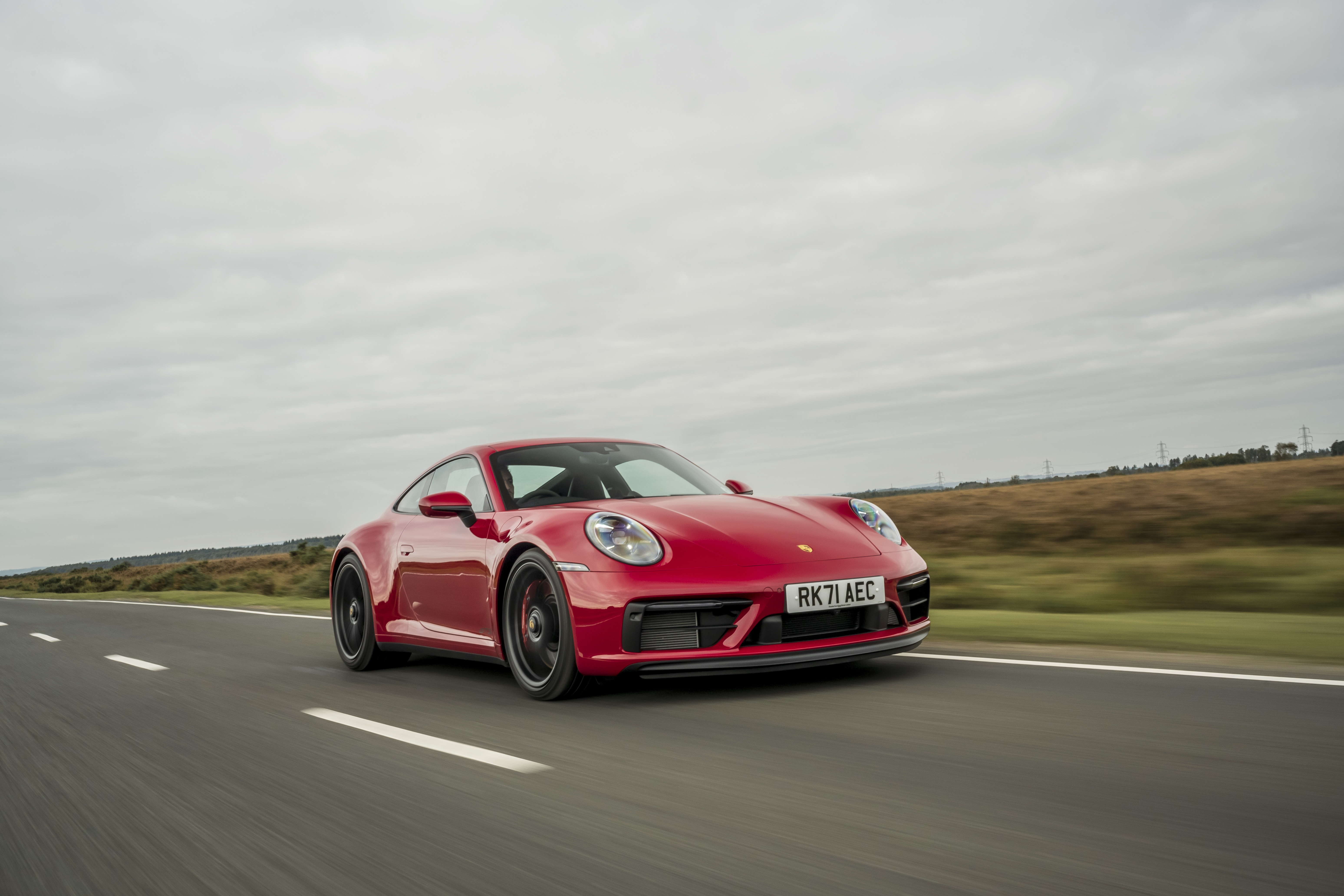 Red Porsche 911 Carrera GTS driving on a road HD Wallpaper