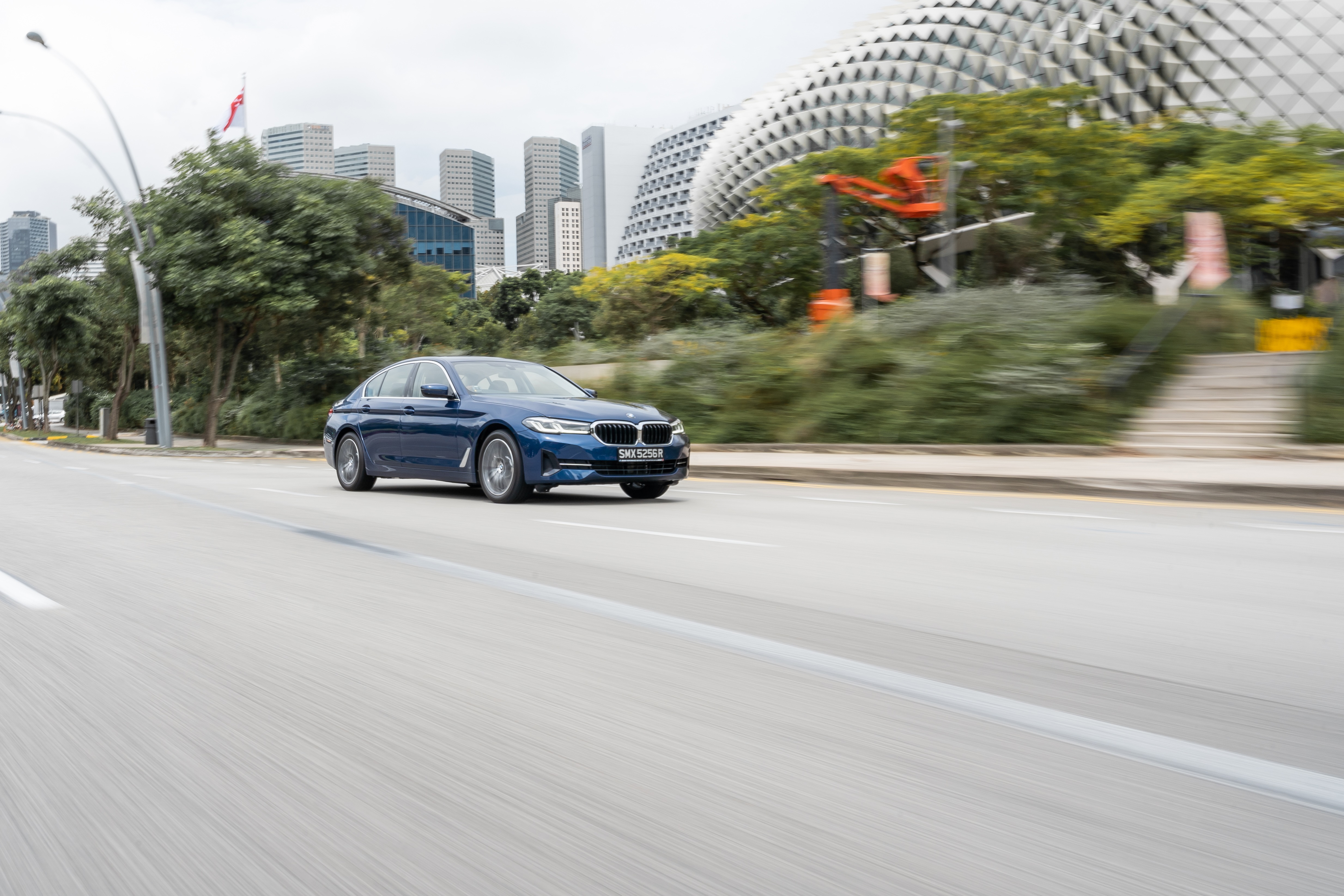 Blue BMW 5 Series 530e Luxury Line driving on road HD Wallpaper