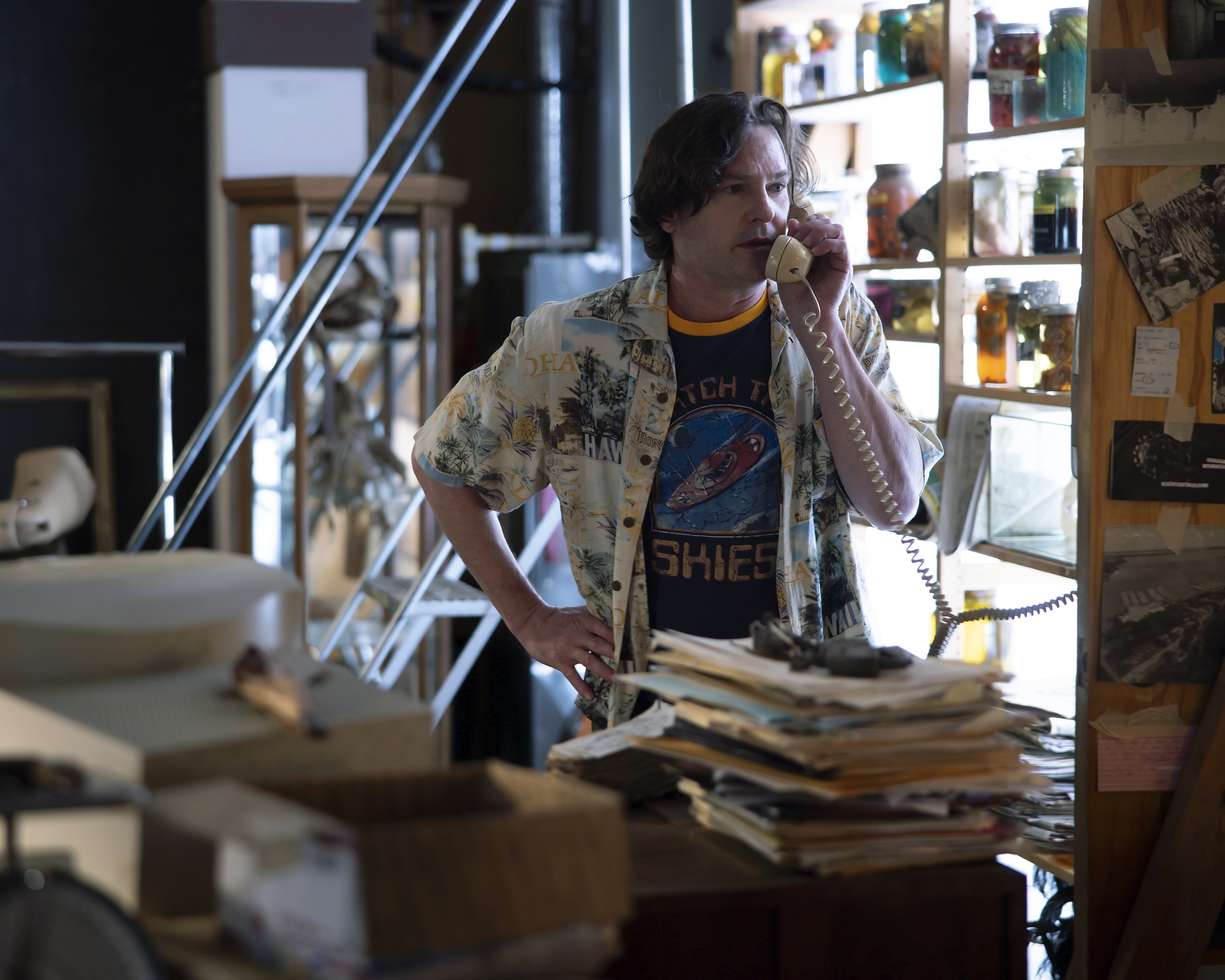 Henry Thomas on the phone in a cluttered room HD Wallpaper