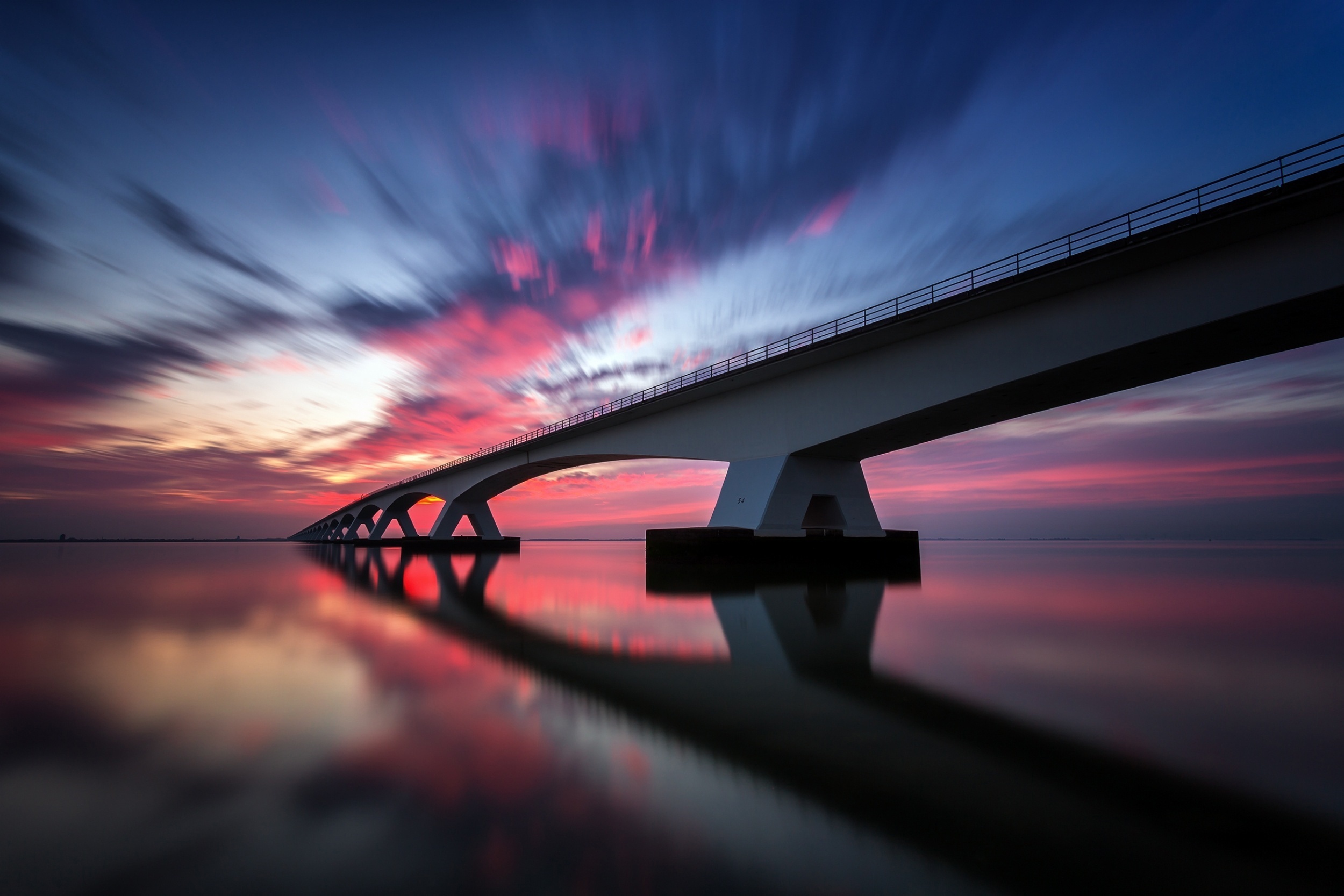 Bridge over water at sunset with reflection HD Wallpaper