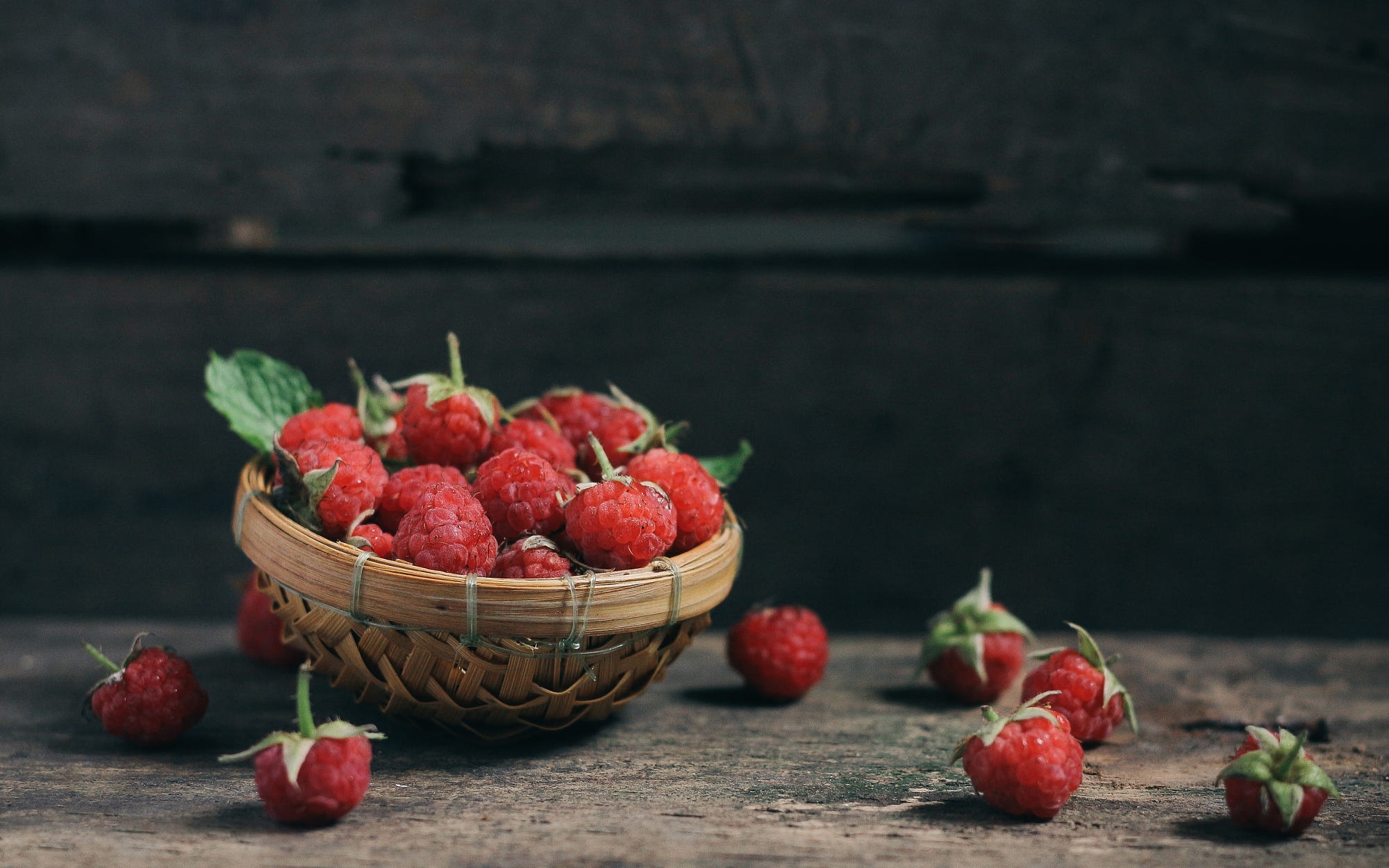 Raspberries in a basket on a wooden table HD Wallpaper
