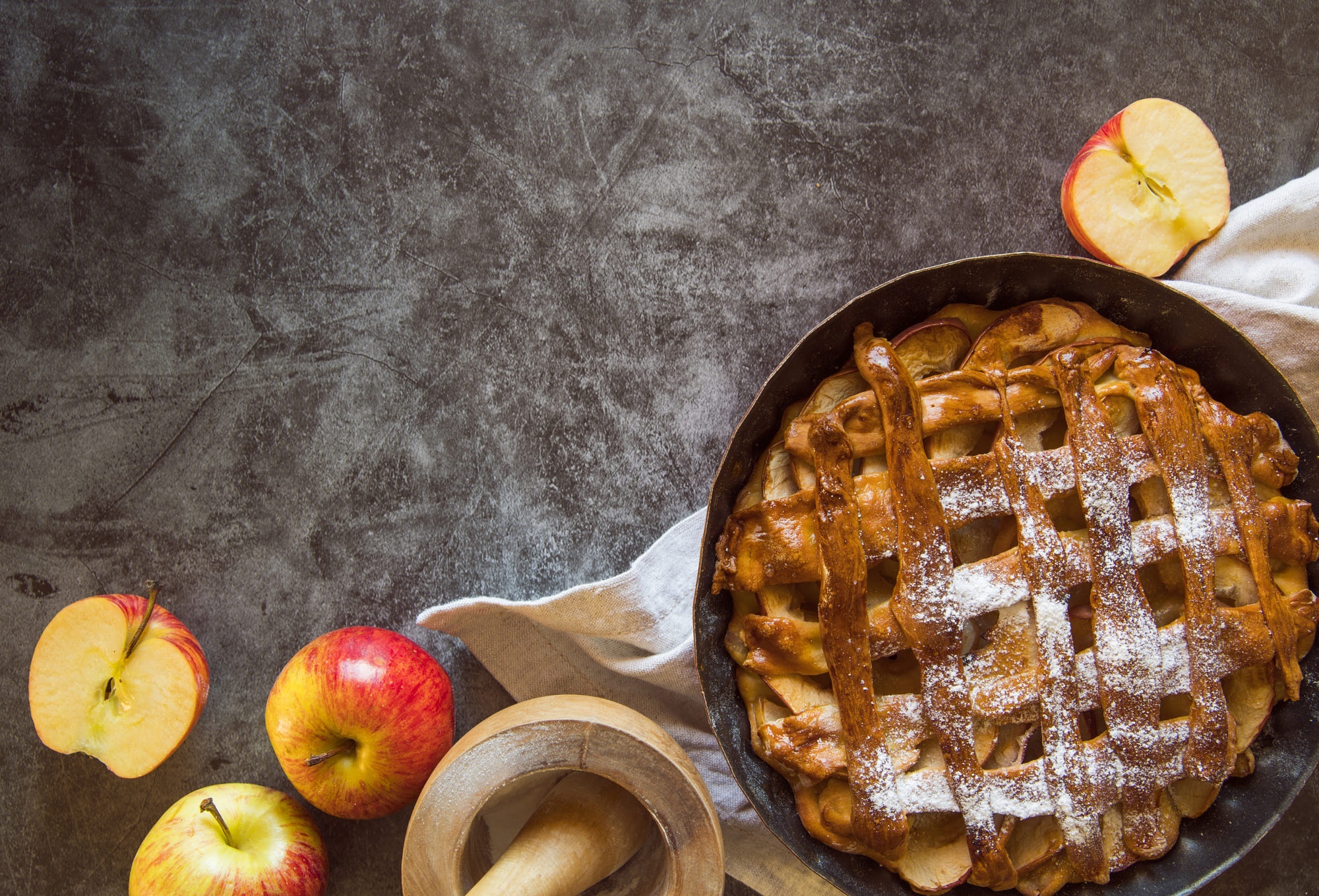 Apple pie with apples and mortar on a dark surface HD Wallpaper